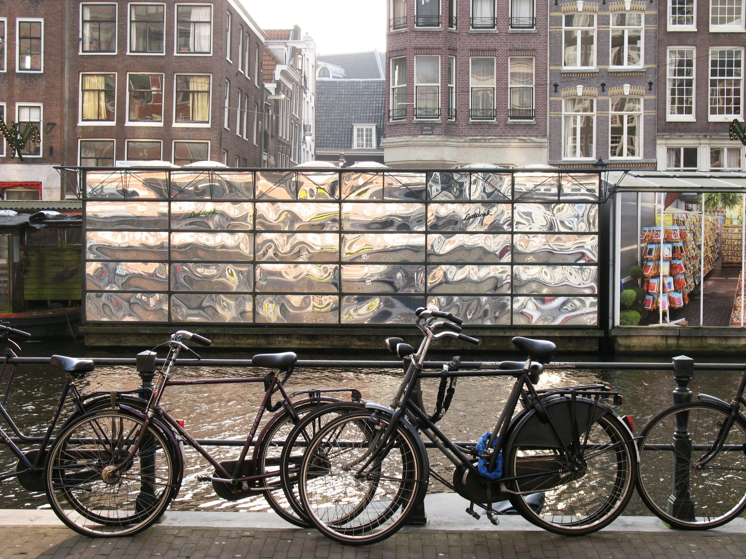 Canoe flutuando sobre o canal de Amsterdã com bicicletas estacionadas na calçada ao fundo. Amsterdam, Holanda. 