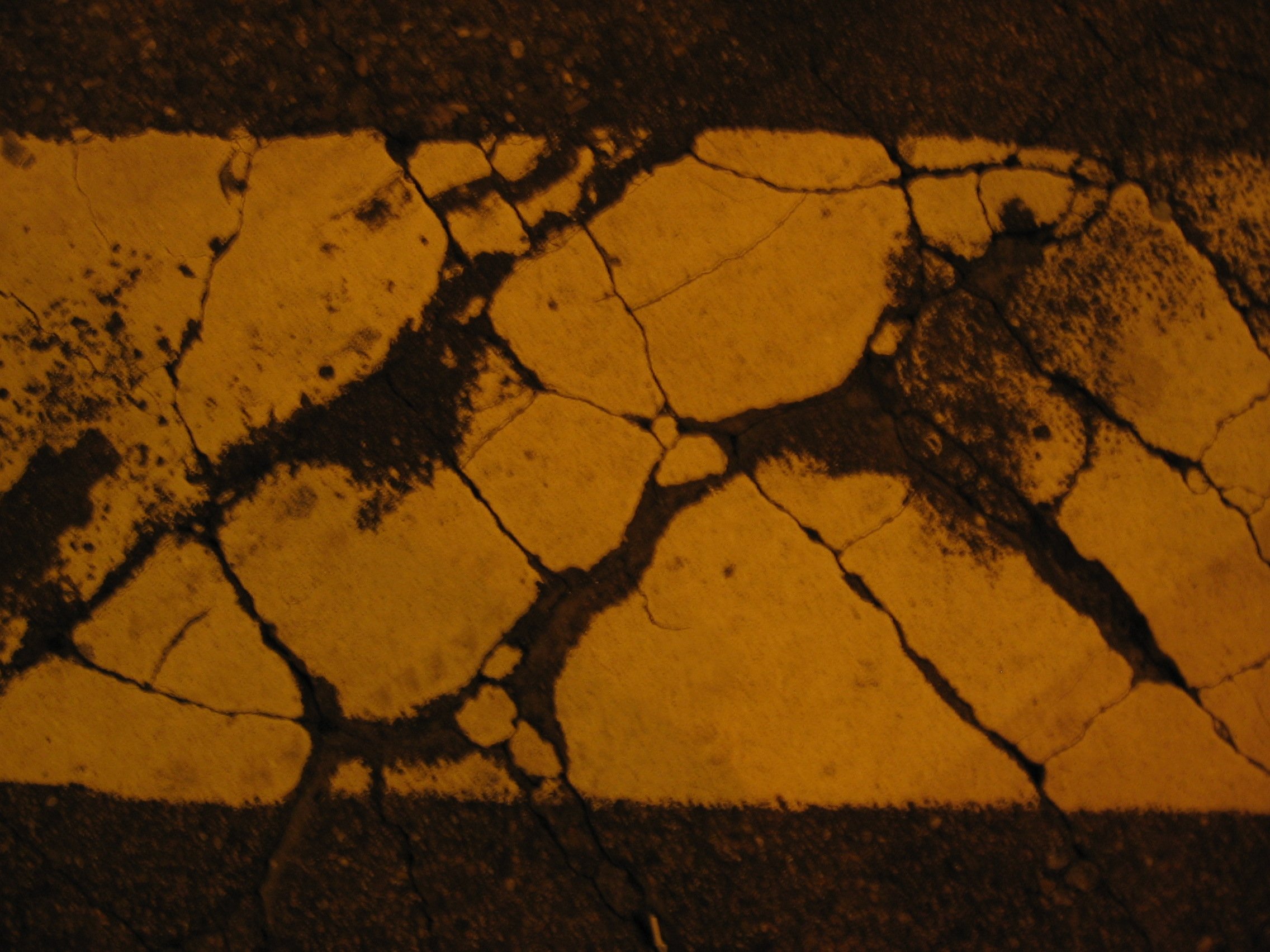 Tinta amarela desgastada em uma rua de asfalto com rachaduras. Amsterdam, Holanda. 