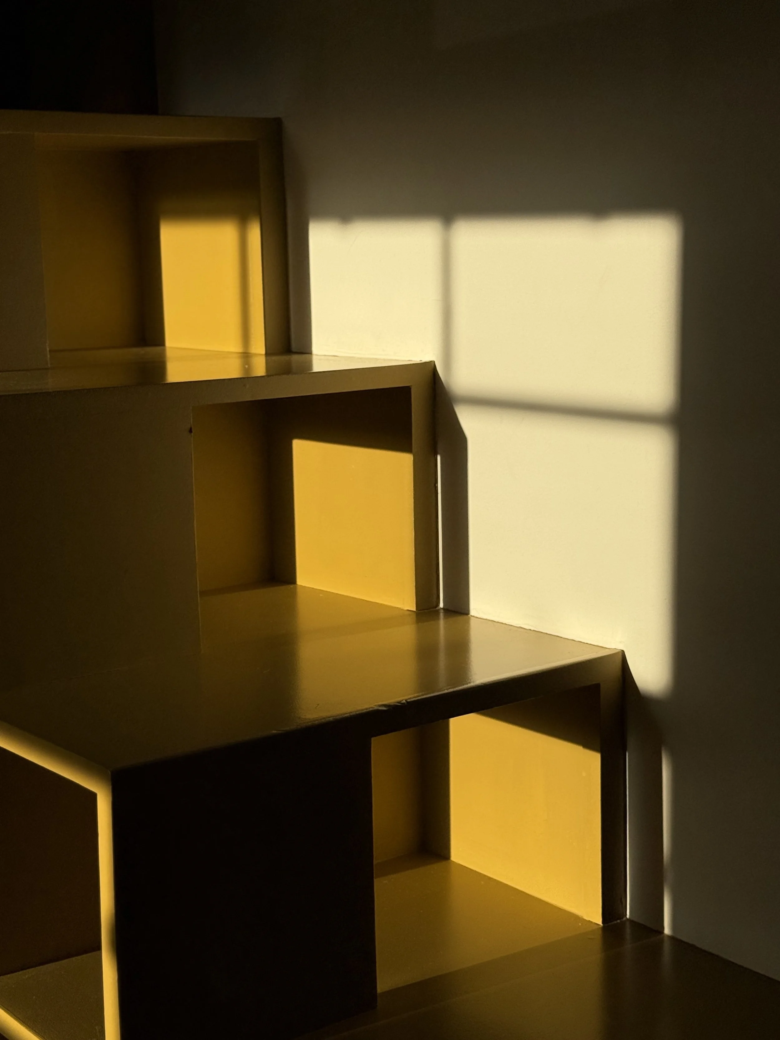 Yellow shelving unit casting shadows on the wall.