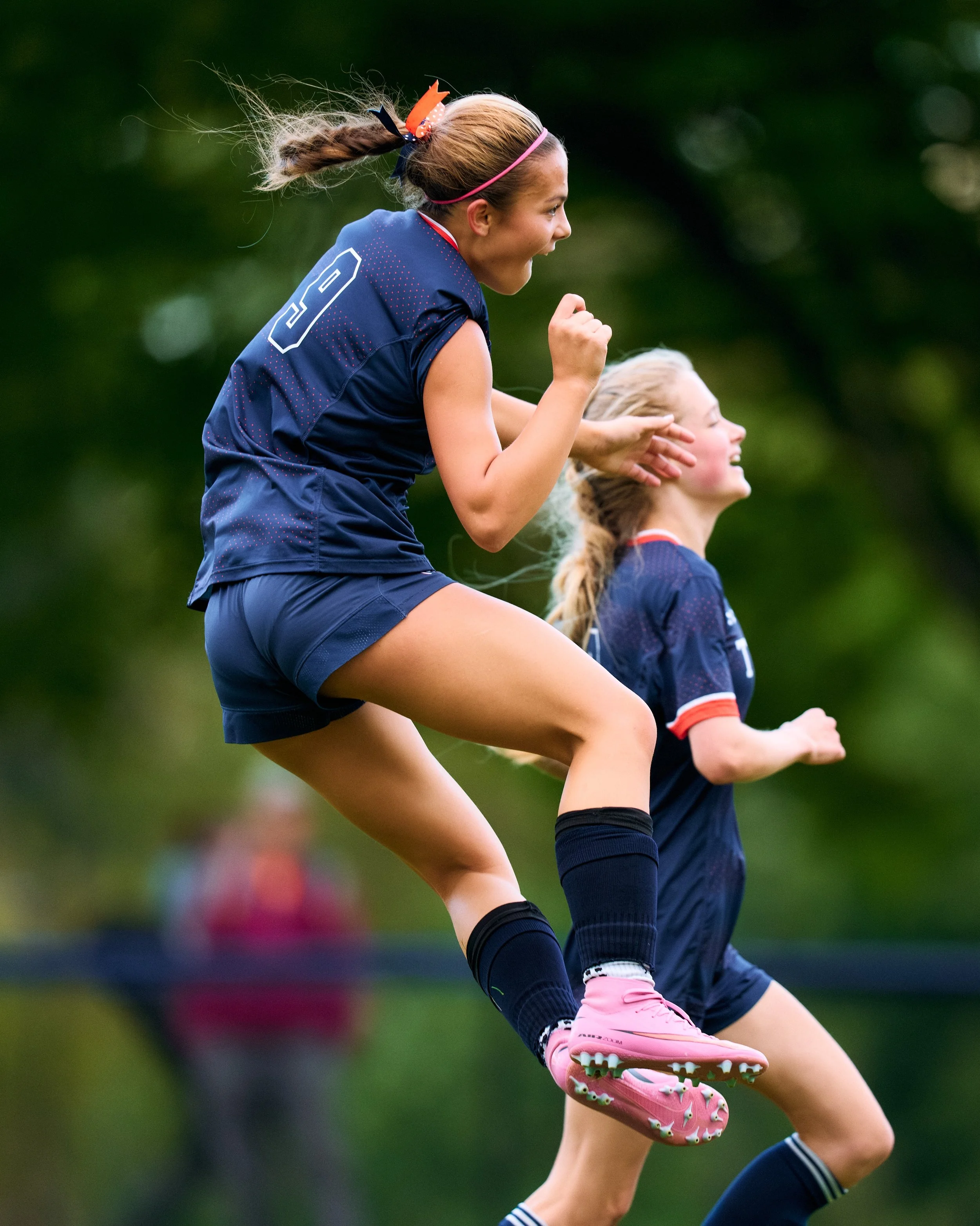 Natalija in a soccer uniform jogging outdoors on a field, celebrating or enjoying themselves.