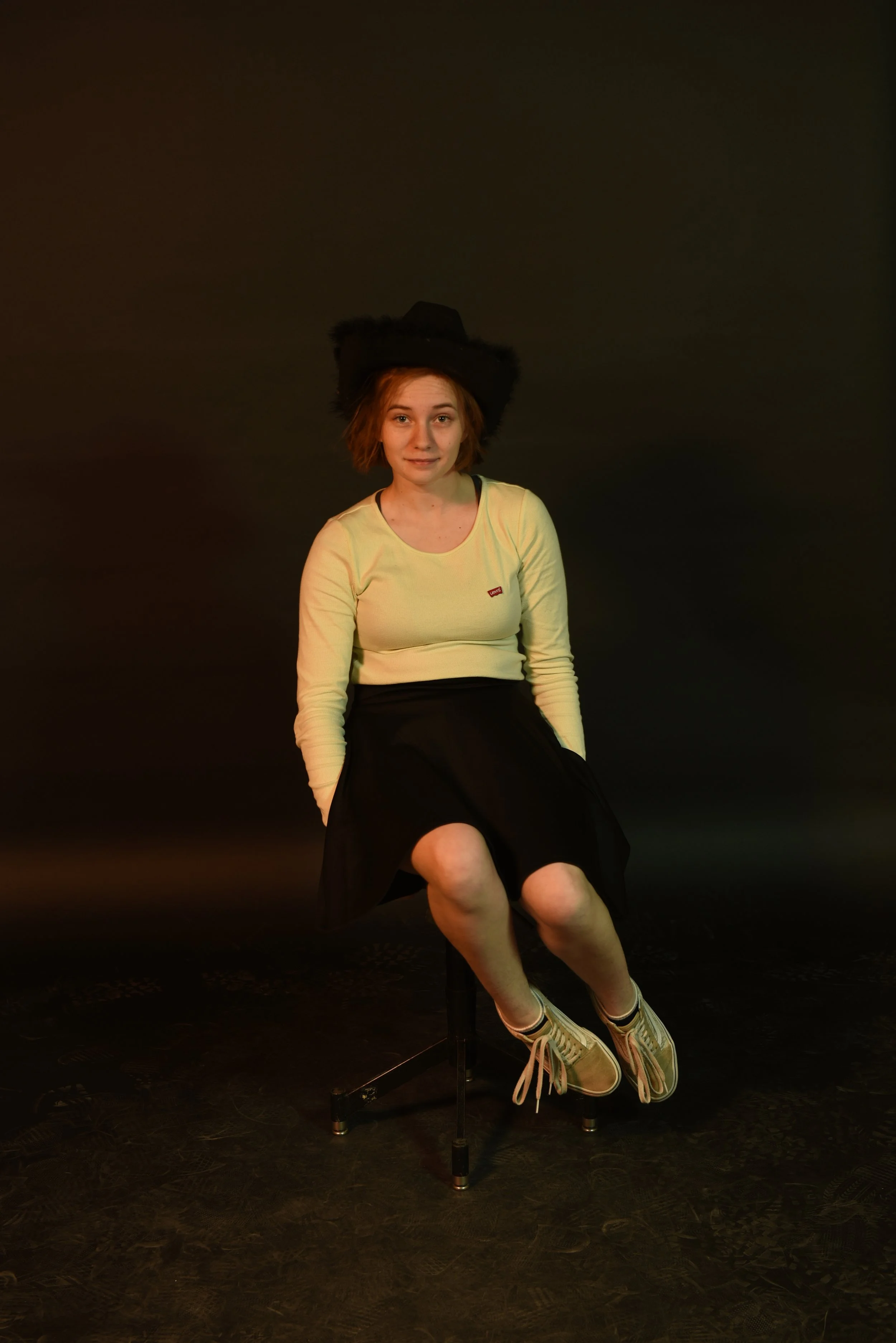 Image of Kathryn sitting on a stool in a studio portrait setting.