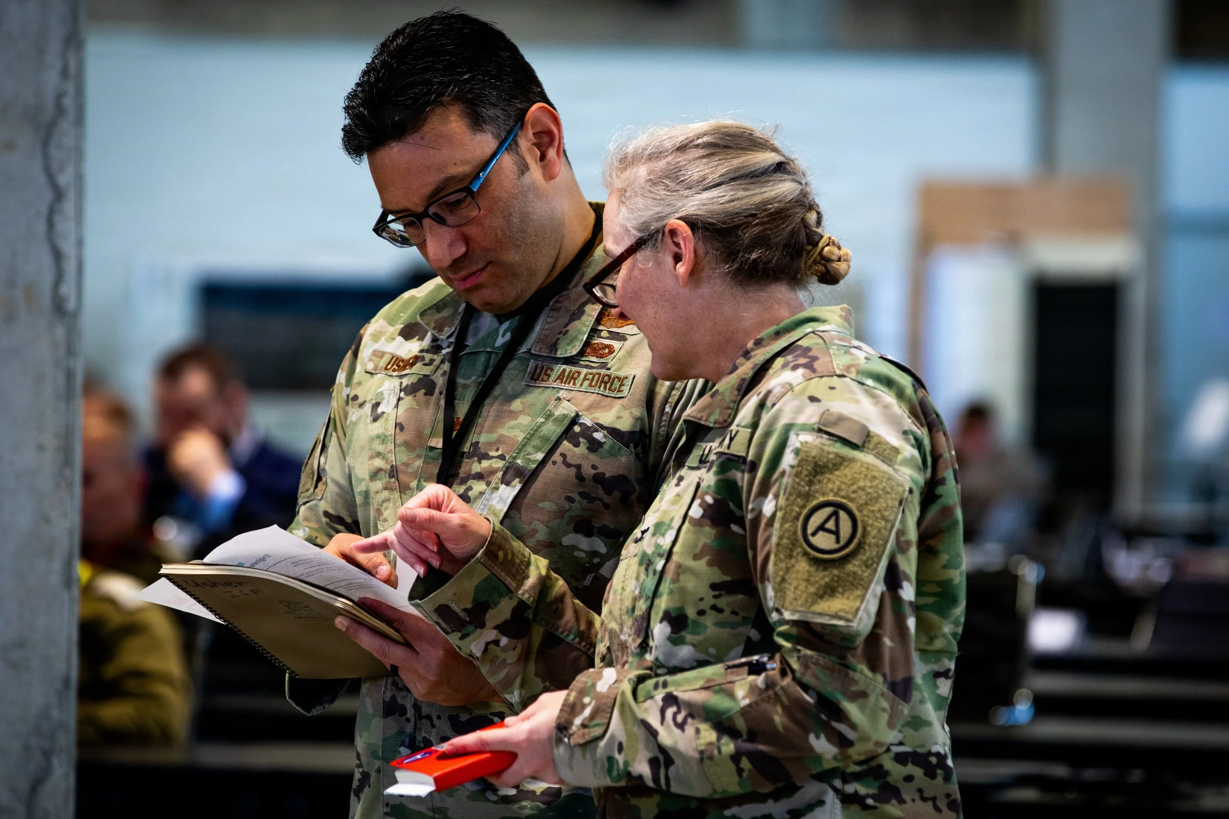 U.S. Air Force Col. Peter Usher and U.S. Army Col. Christina Burton review notes before briefing leadership on humanitarian assistance operations inside the Civil-Military Coordination Center (CMCC) on Dec. 6, 2025. (U.S. Army photo by Sgt. Kathryn S