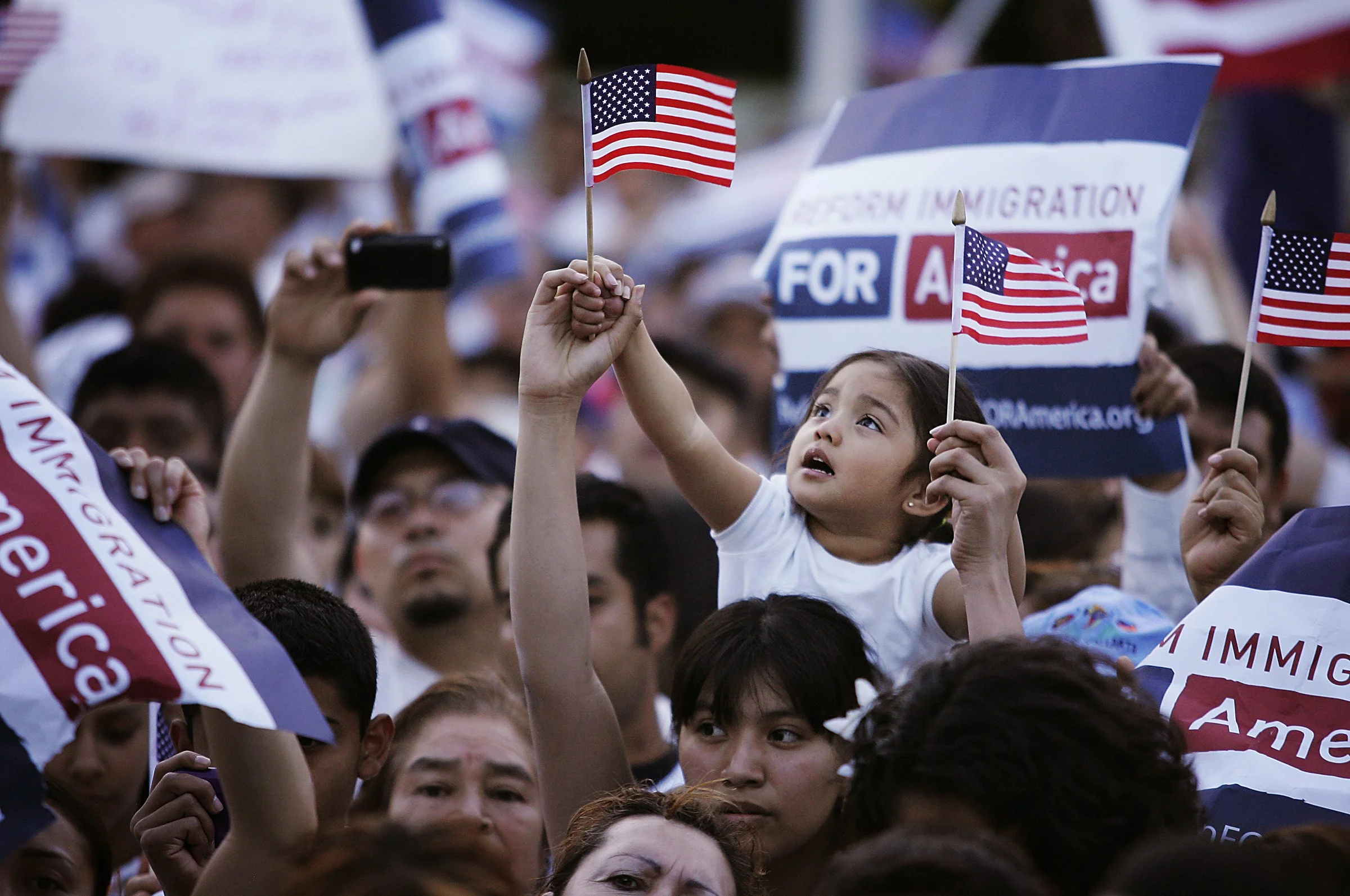 2 year old Ariana Ventura looks up towards her American flag while sitting on her sister Diana's shoulders during an immigration reform rally in downtown Las Vegas on May 1, 2010.