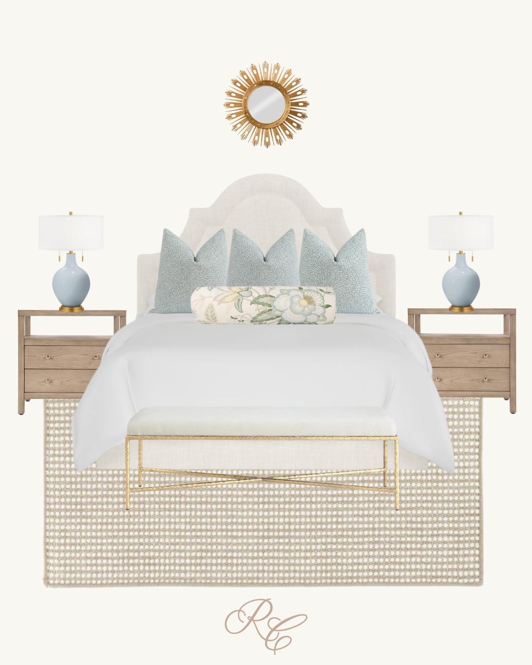 A modern white bed with a headboard, three decorative blue pillows, a floral bolster pillow, two bedside tables with blue lamps, a gold and white bench, a beige patterned rug, and a starburst mirror on the wall above the bed.