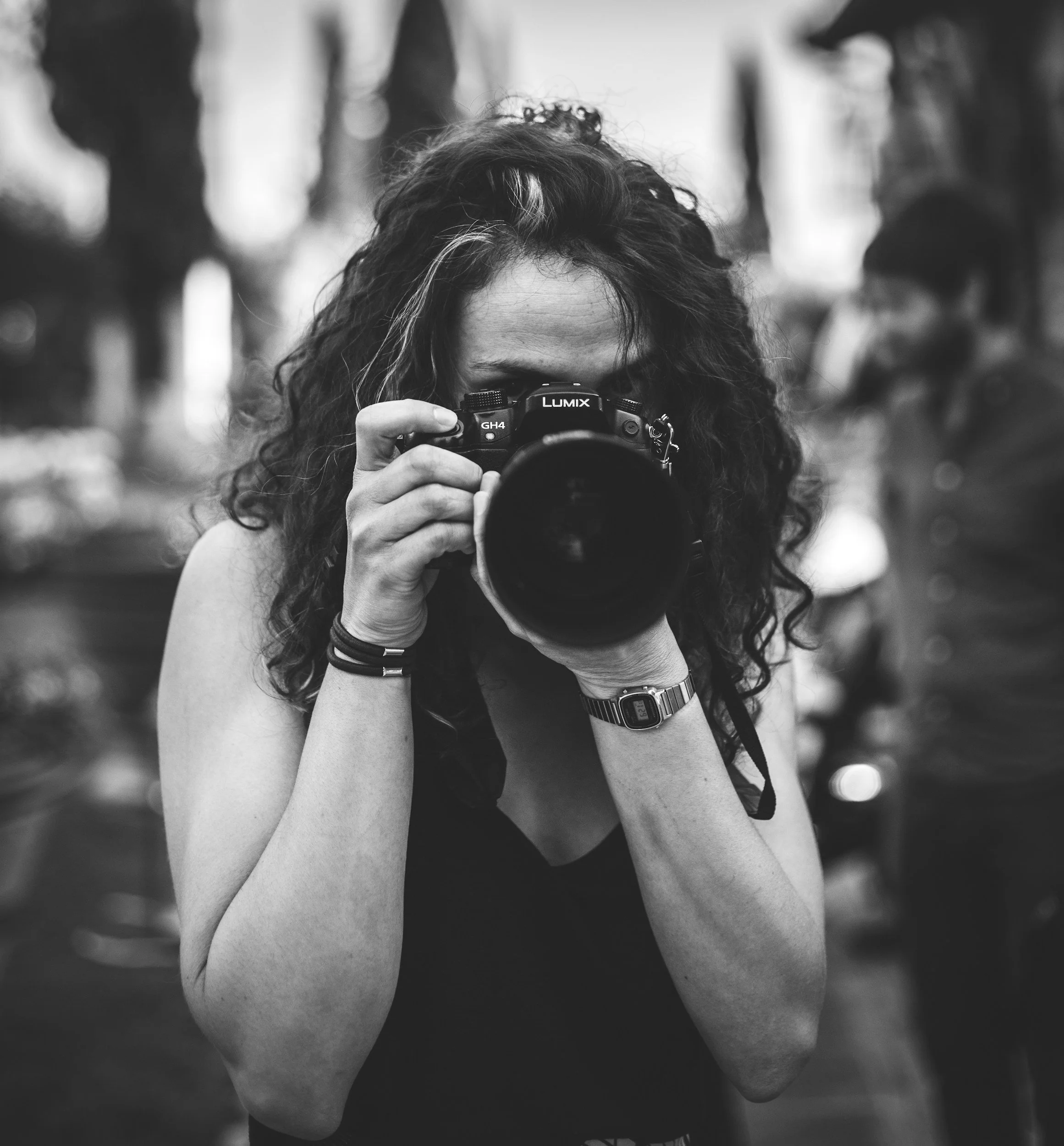 A woman with curly hair taking a photograph with a camera, black and white photo