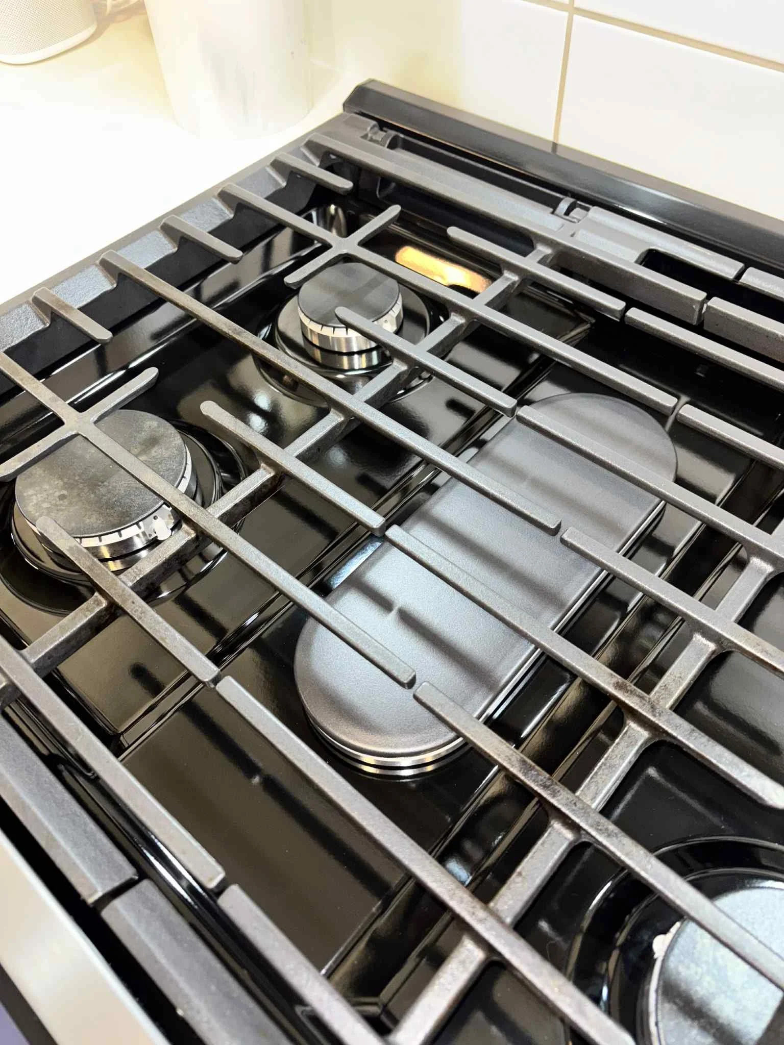 Close-up view of a black gas stove with four burners in a kitchen.