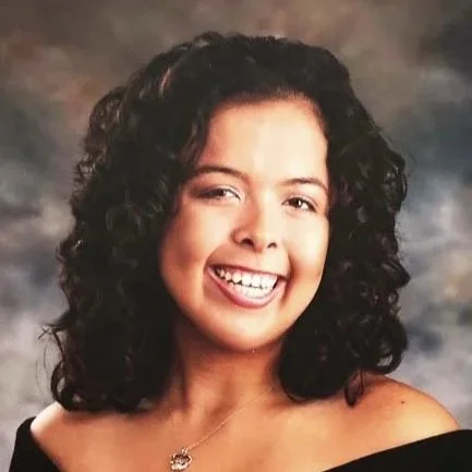 Smiling young woman with curly dark hair in a portrait setting