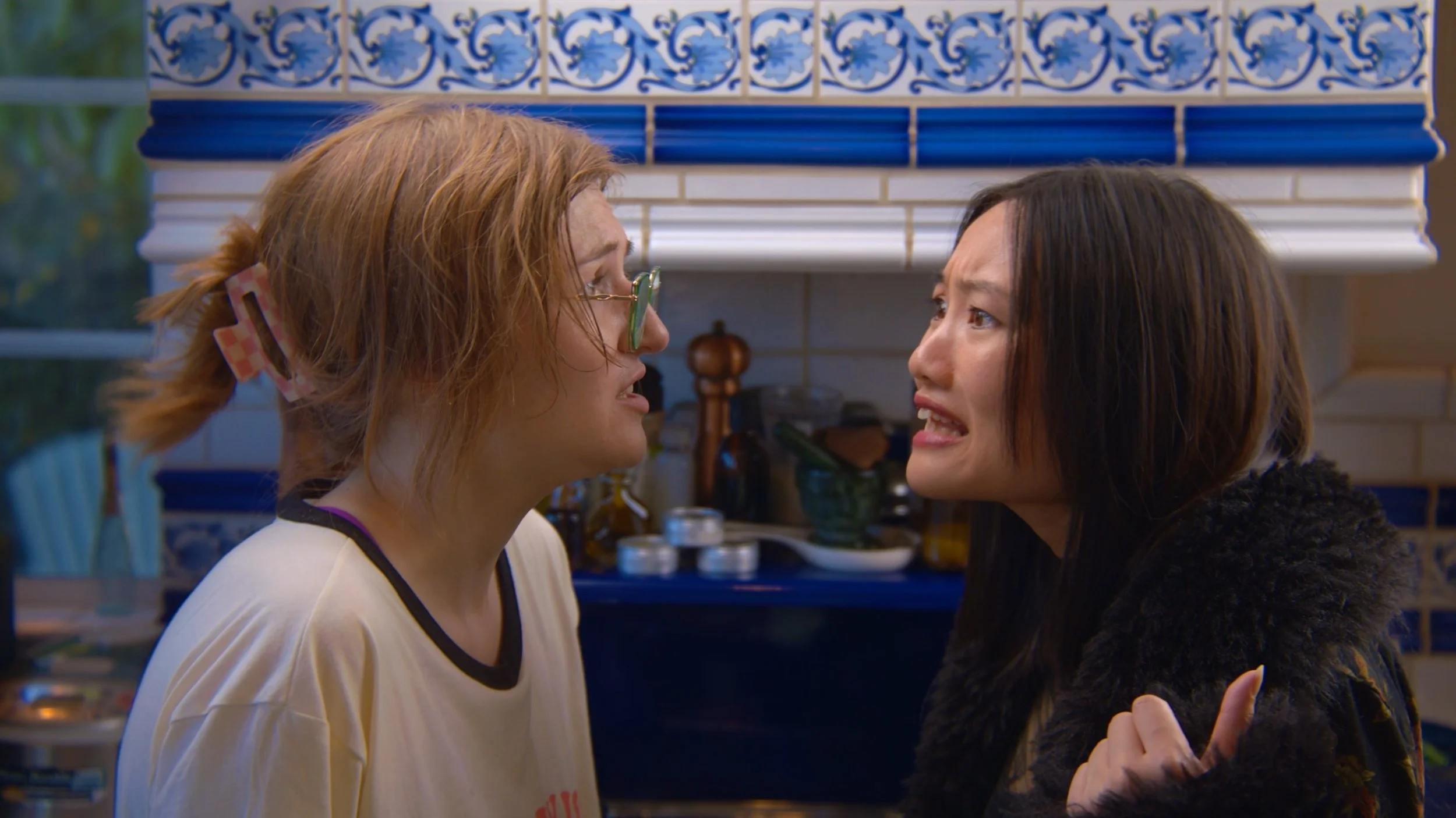 Two women having an intense argument face-to-face in a kitchen.