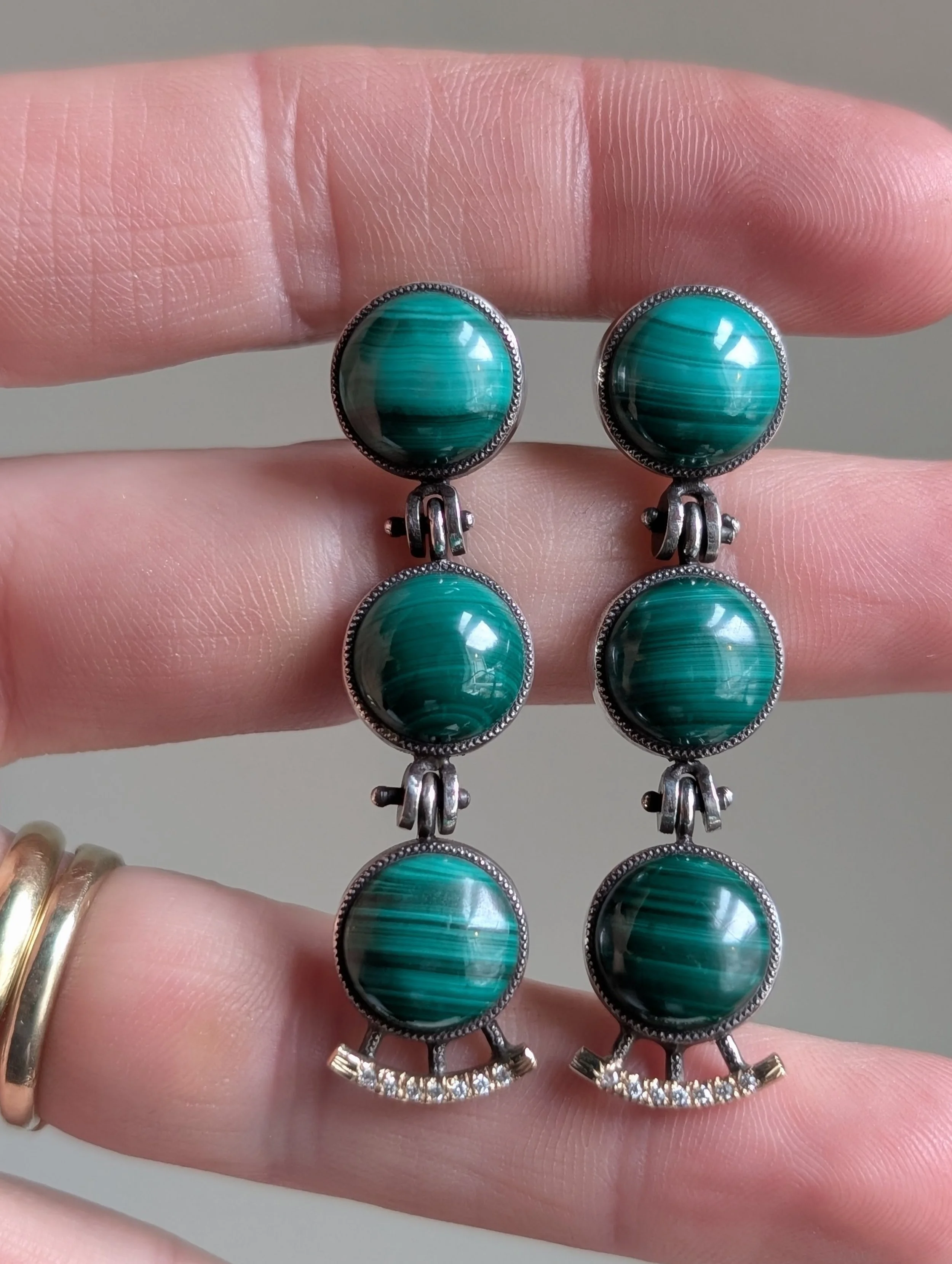 Pair of dangling earrings with round turquoise stones set in silver, with three stones on each earring connected by small silver links, and small clear stones at the bottom.