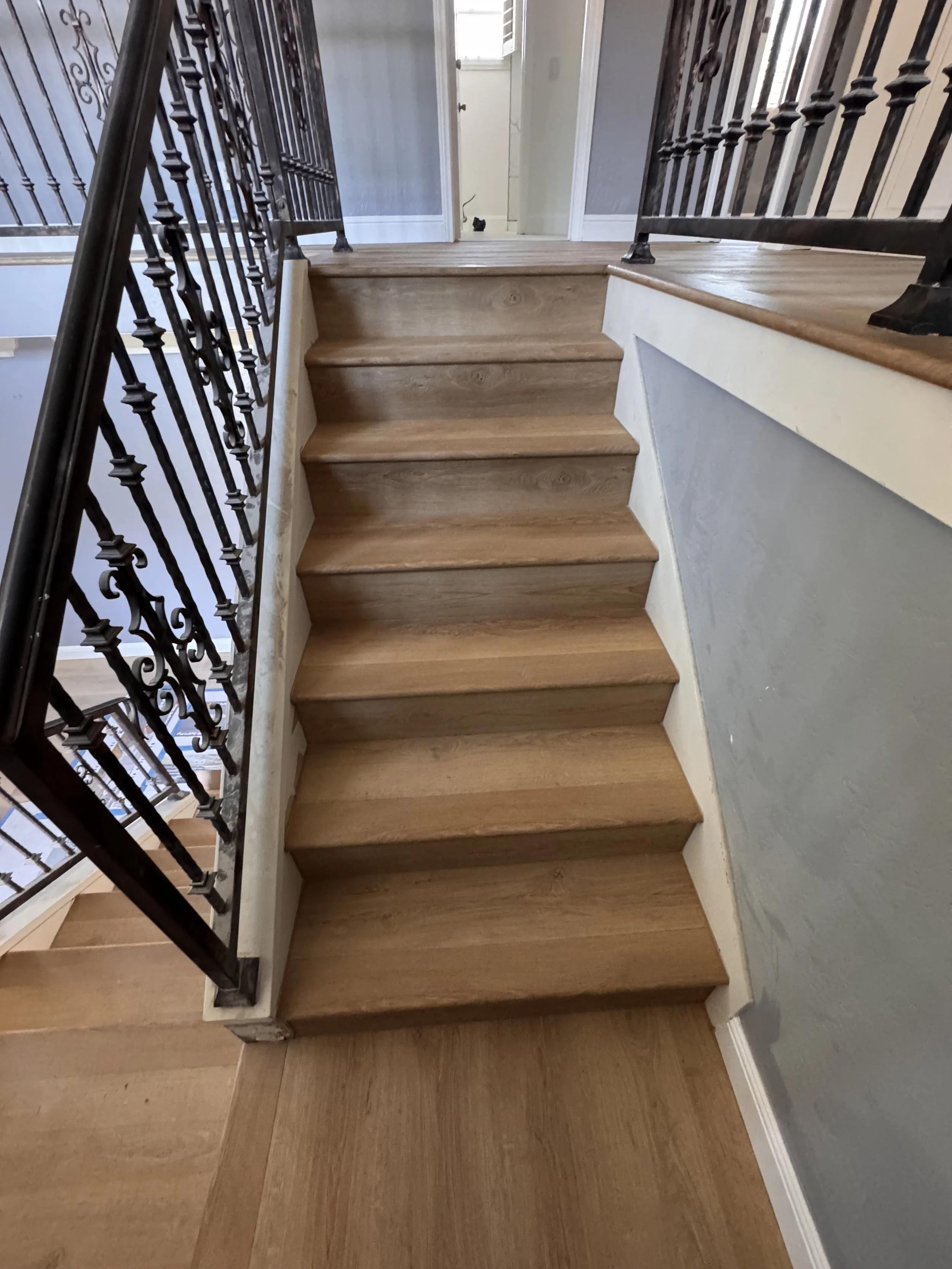 Wooden staircase with black metal railing leading to an upper floor in a house interior.