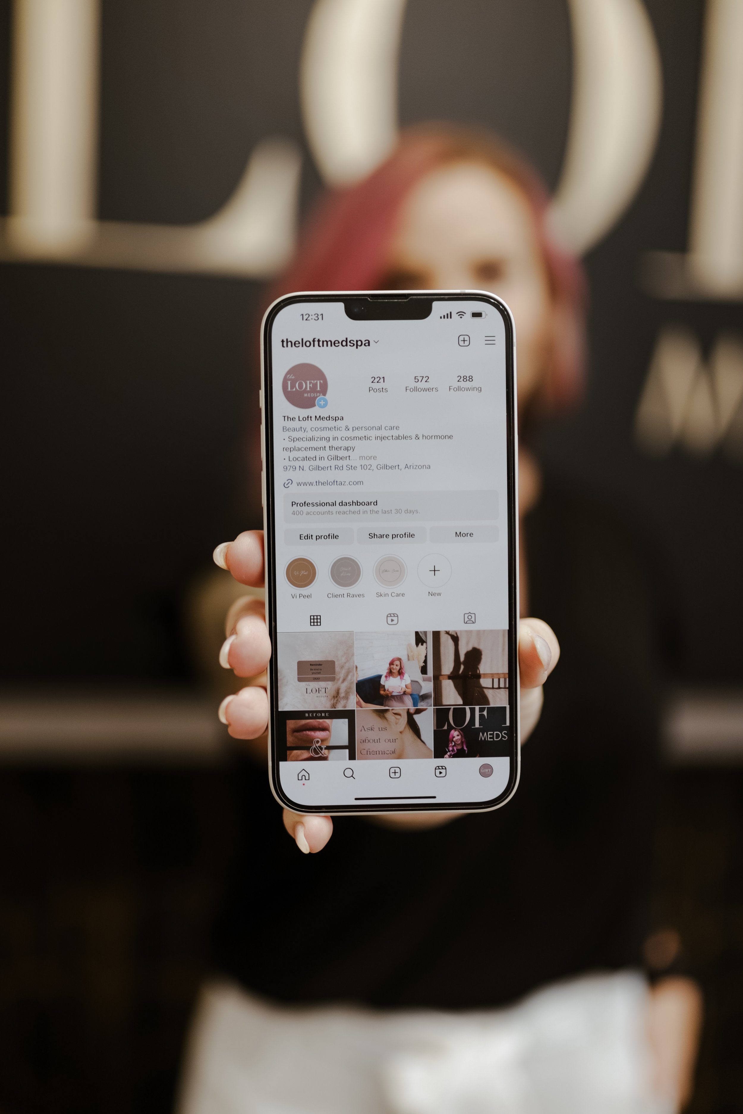 Person holding a smartphone displaying an Instagram profile for The Loft Medspa.