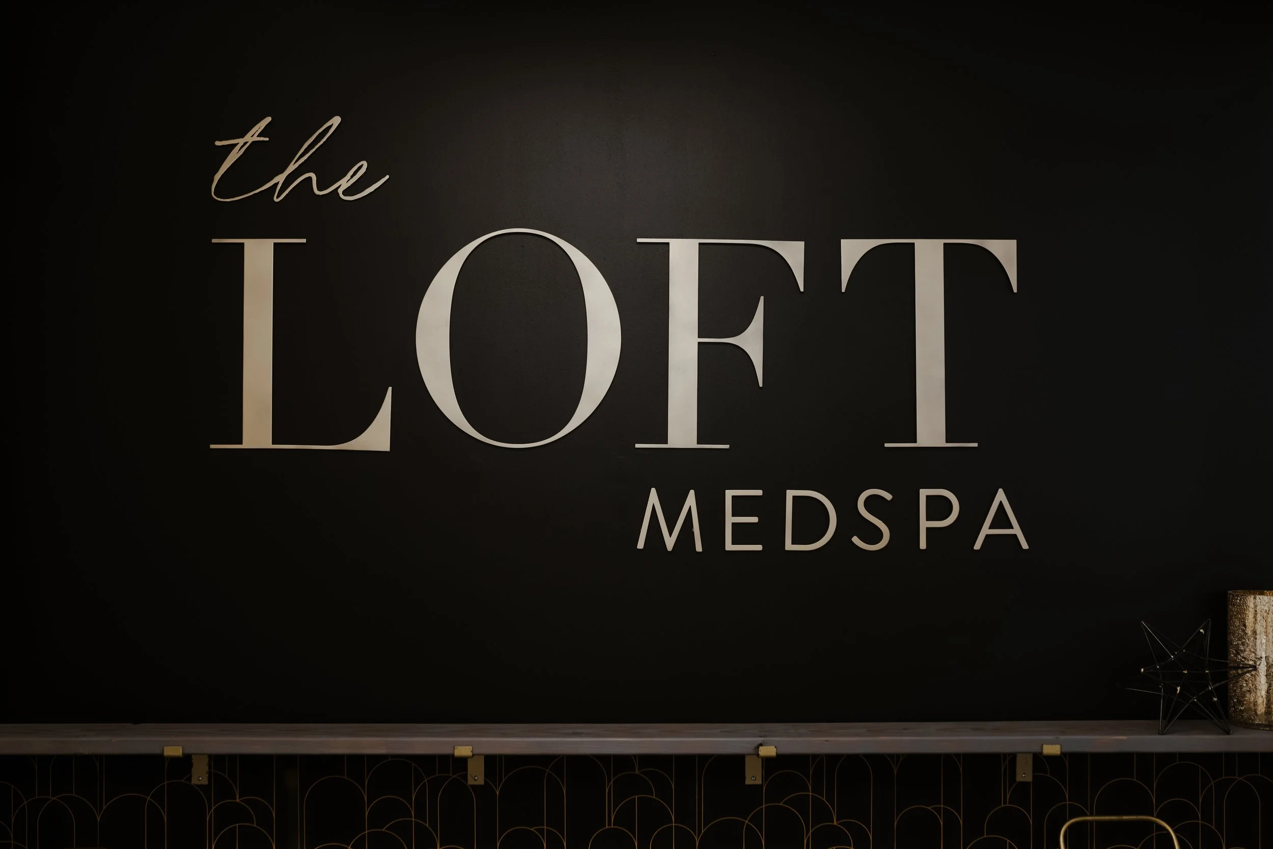 Sign reading 'The Loff Medspa' on a black wall with modern decor.