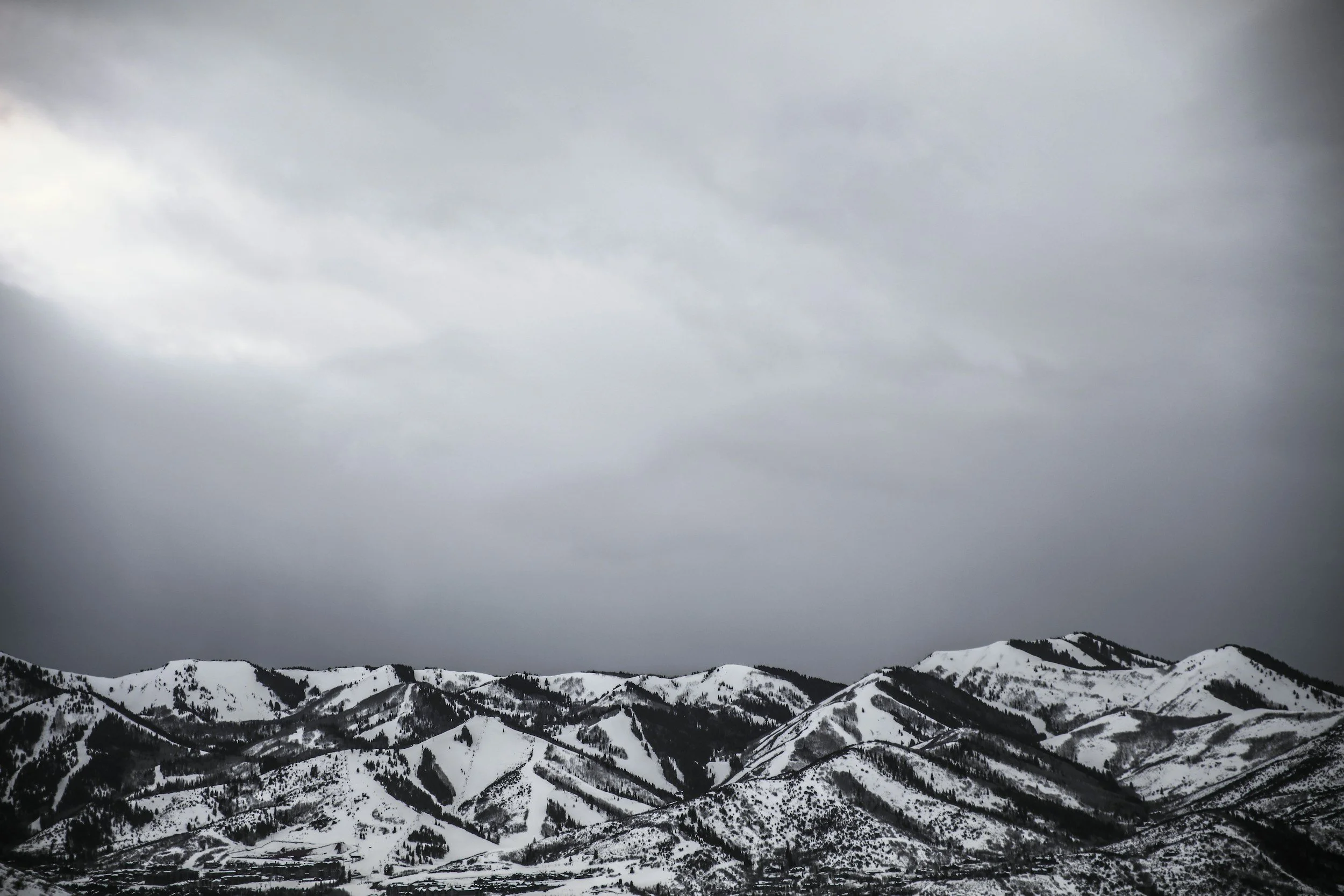 Snow-covered mountain range under a dark, cloudy sky.