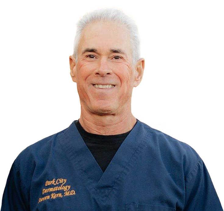 A smiling middle-aged man with short white hair, wearing navy medical scrubs with a name badge that reads 'Park City Dermatology, Joreen Klem, M.D.'