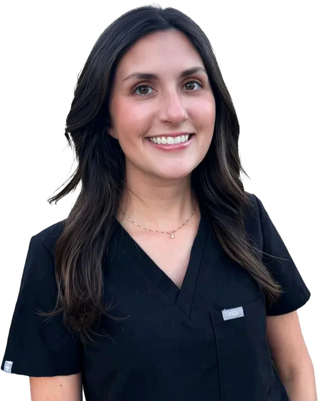 Smiling woman with long dark hair wearing navy medical scrubs and a delicate necklace.