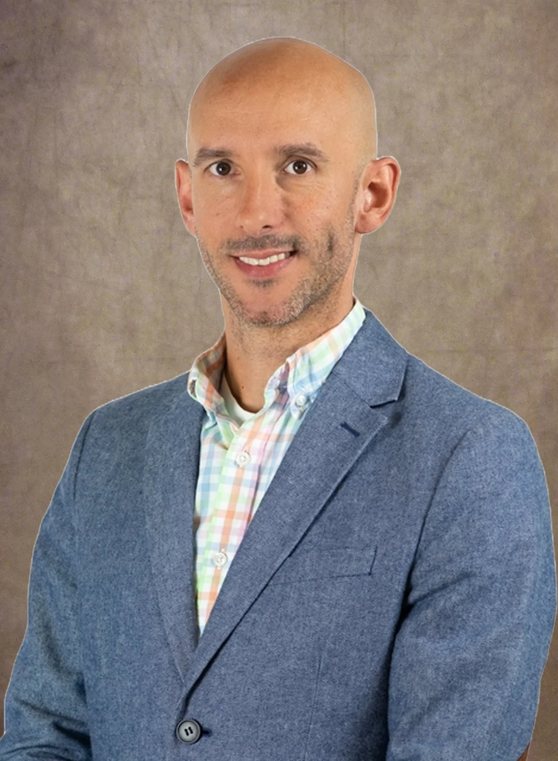 Man in a blue blazer and pastel checkered shirt with a neutral background.