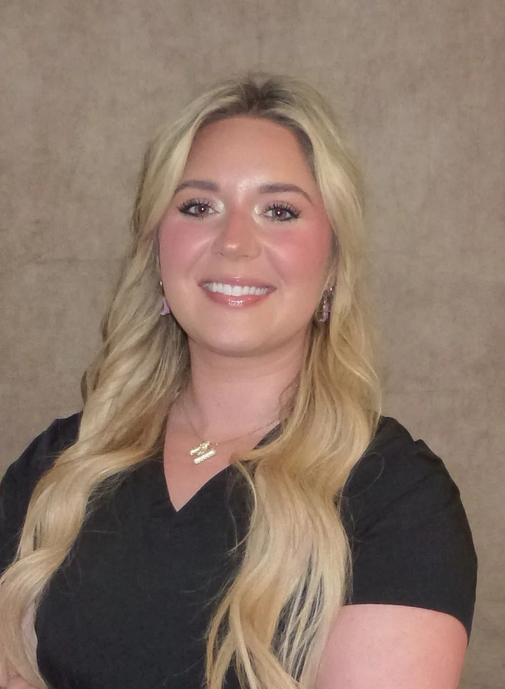 Smiling person with long blonde hair and a black shirt.