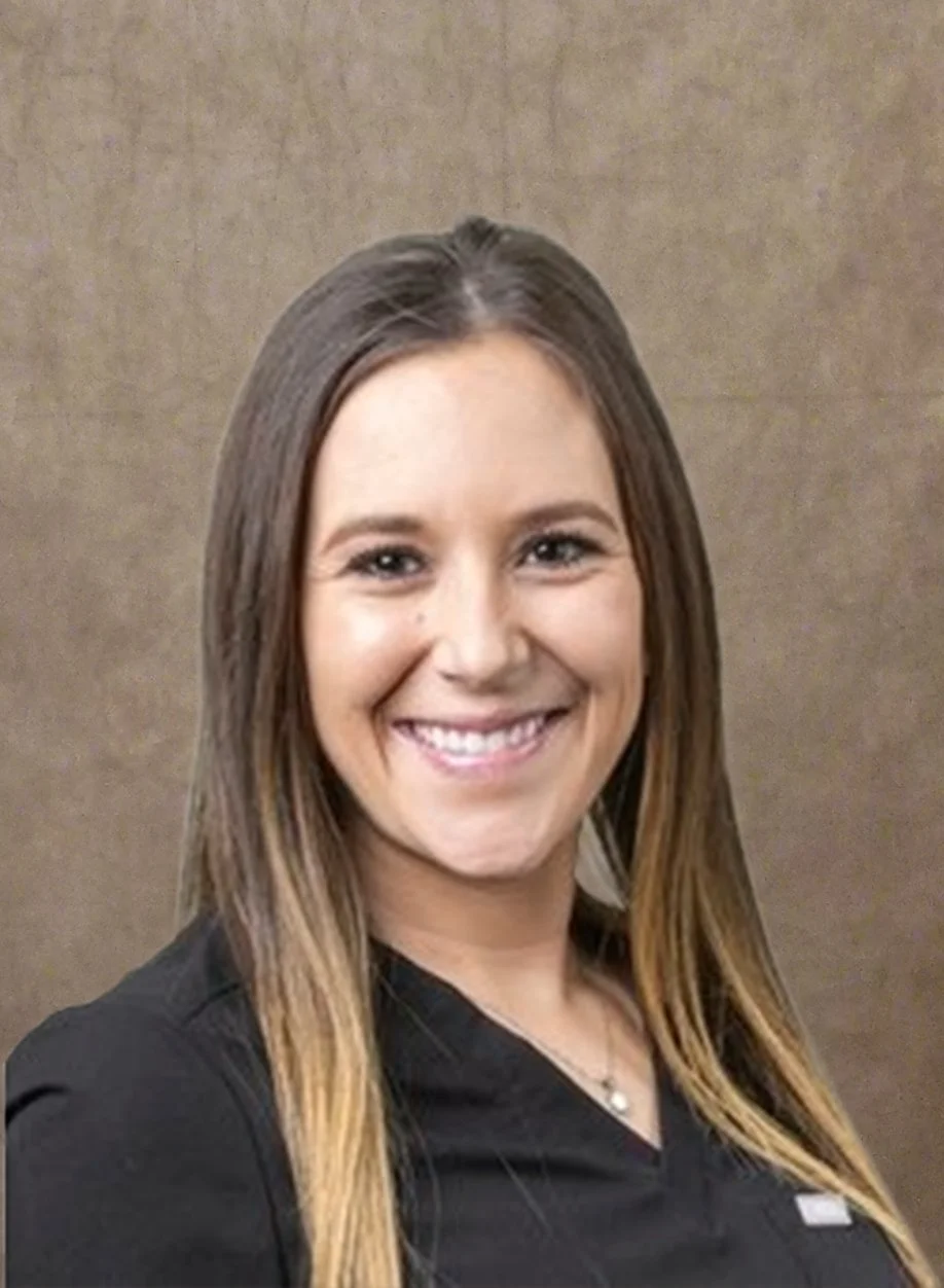 Woman smiling with long hair wearing a black top against a brown background.