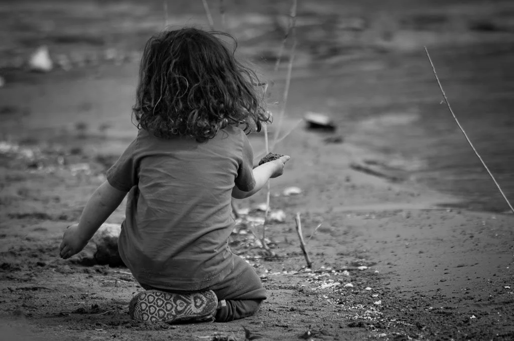 Child facing away from the camera playing in dirt.