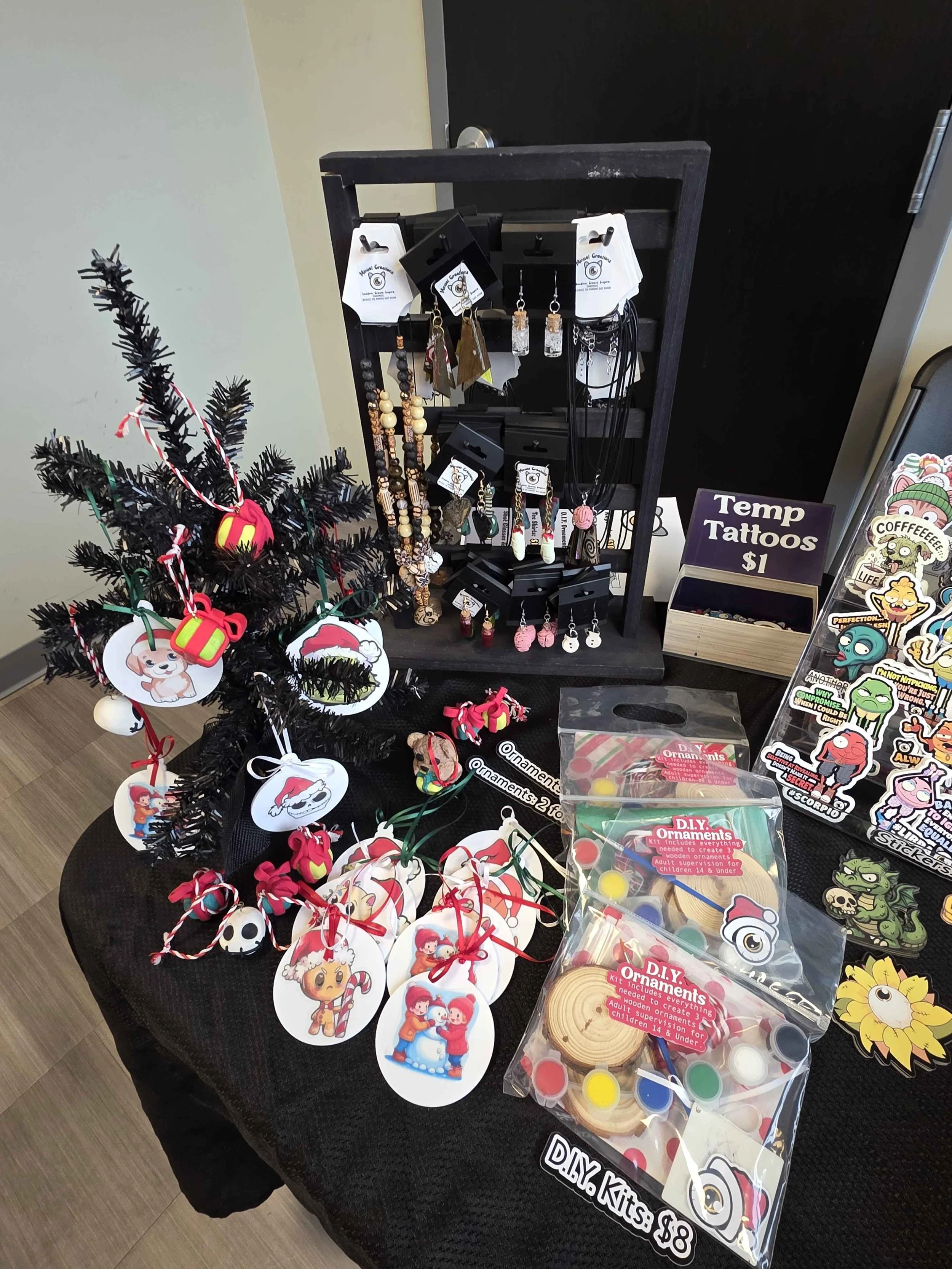 Christmas ornaments, jewelry, temporary tattoos, and DIY craft kits displayed on a black table.