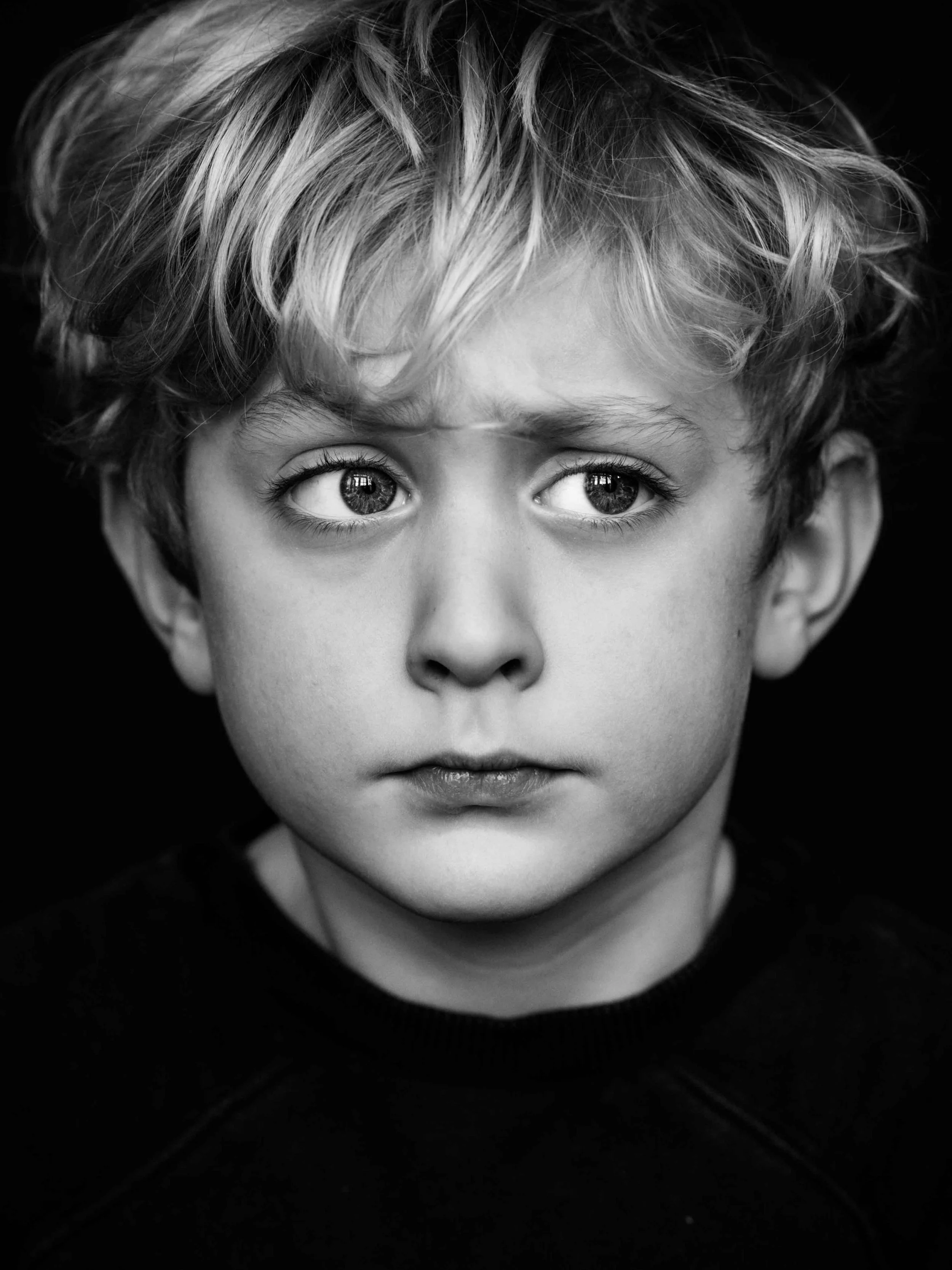 Zwart wit professioneel portret van een jongen van 5 jaar met blonde krullen