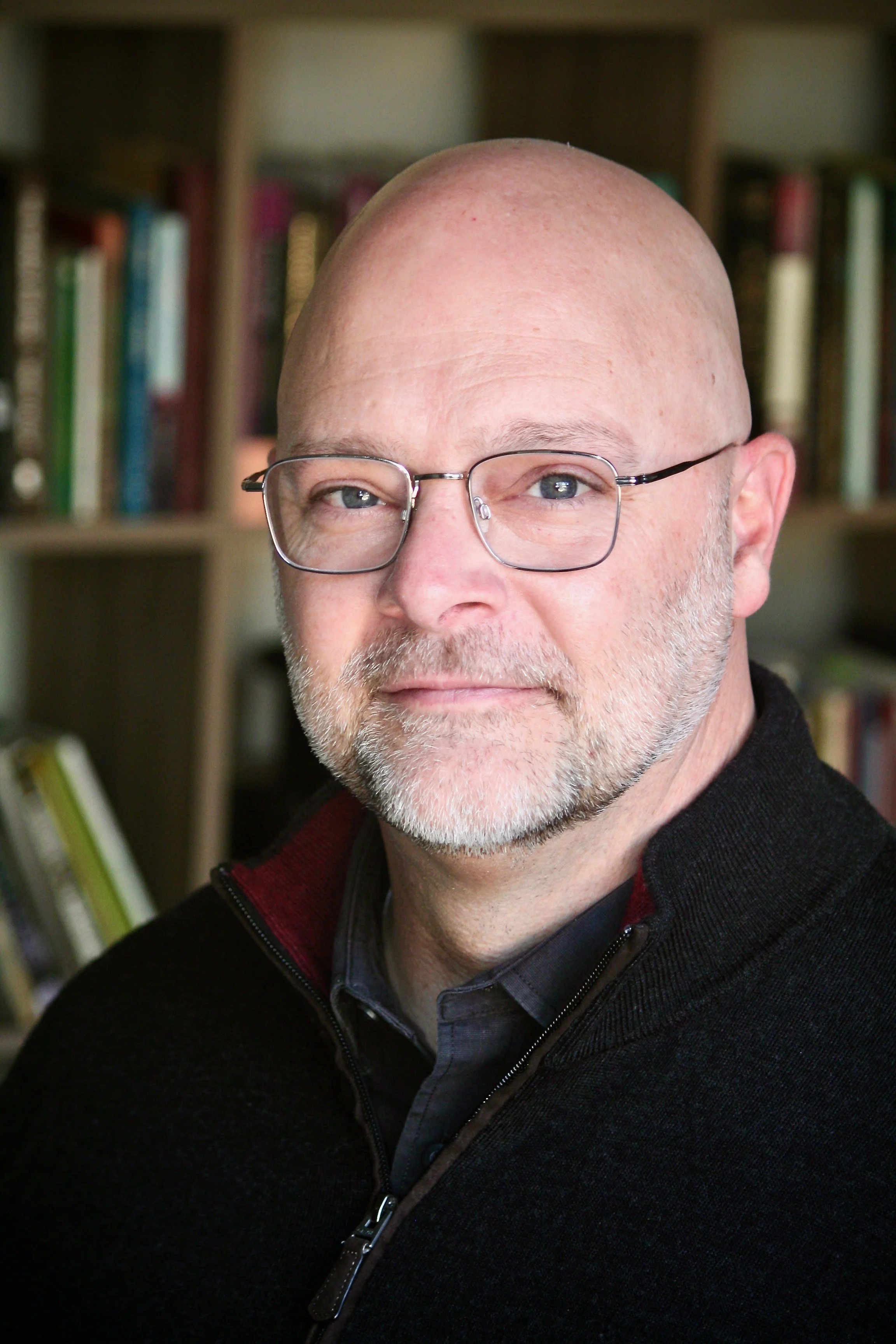 Senior pastor Ryan Tompkins with a background of books.  Ryan is an experienced pastor in the Presbyterian and Anglican tradition. He is also a Licensed Professional Counselor.