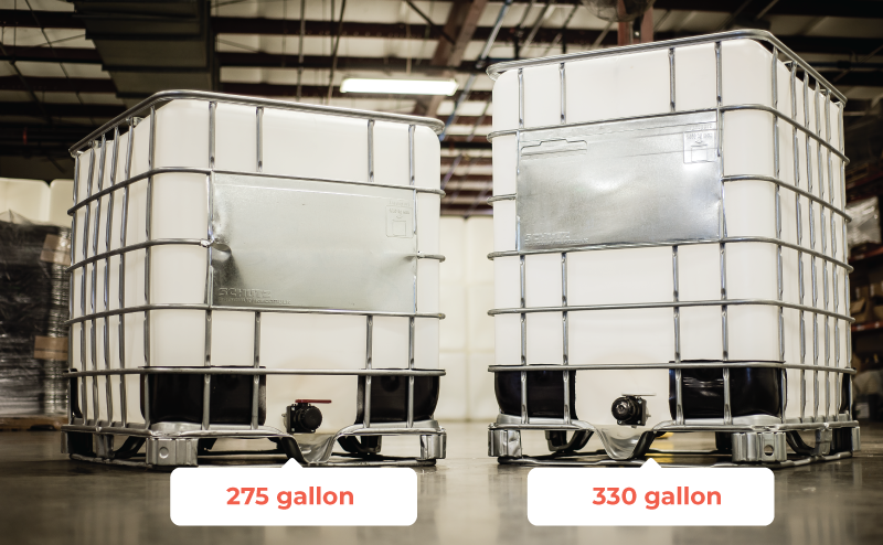 Two large industrial tanks labeled as 275-gallon and 330-gallon containers, made of white plastic with metal reinforcement, sitting on a concrete floor in a warehouse.