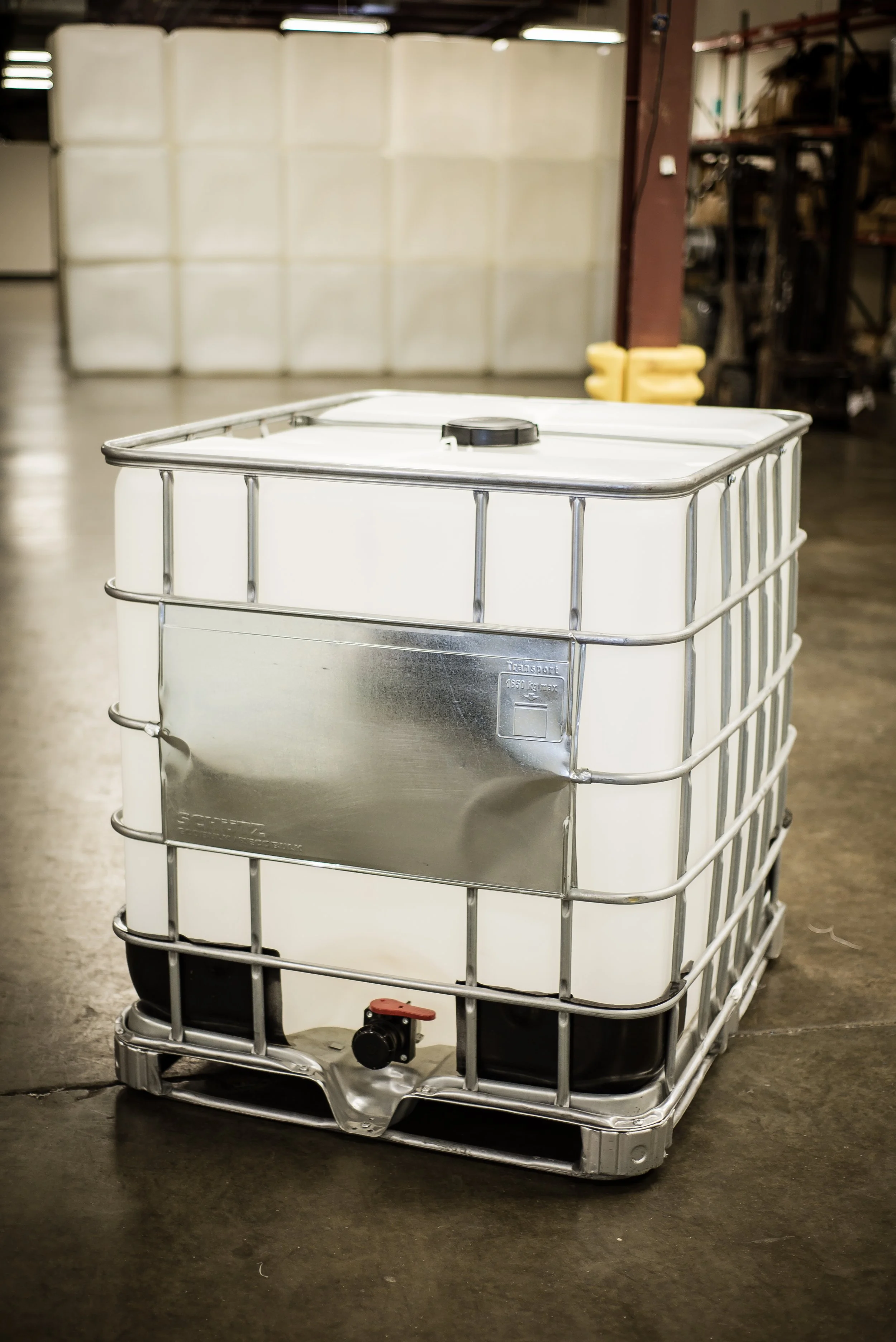 A large white industrial shipping container on a black plastic pallet in a warehouse.