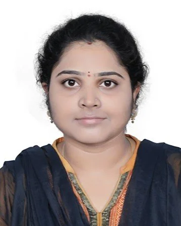 Portrait of a woman with dark hair in a bun, wearing a traditional dark blue and gold outfit, with a neutral expression against a plain white background.