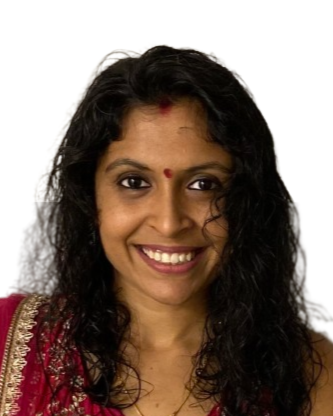 Headshot of a woman with dark curly hair, wearing traditional Indian attire and a bindi on her forehead, smiling at the camera.