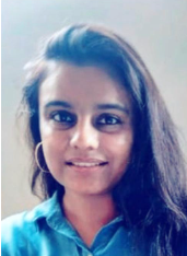 A young woman with long dark hair, wearing a blue top, smiling at the camera.