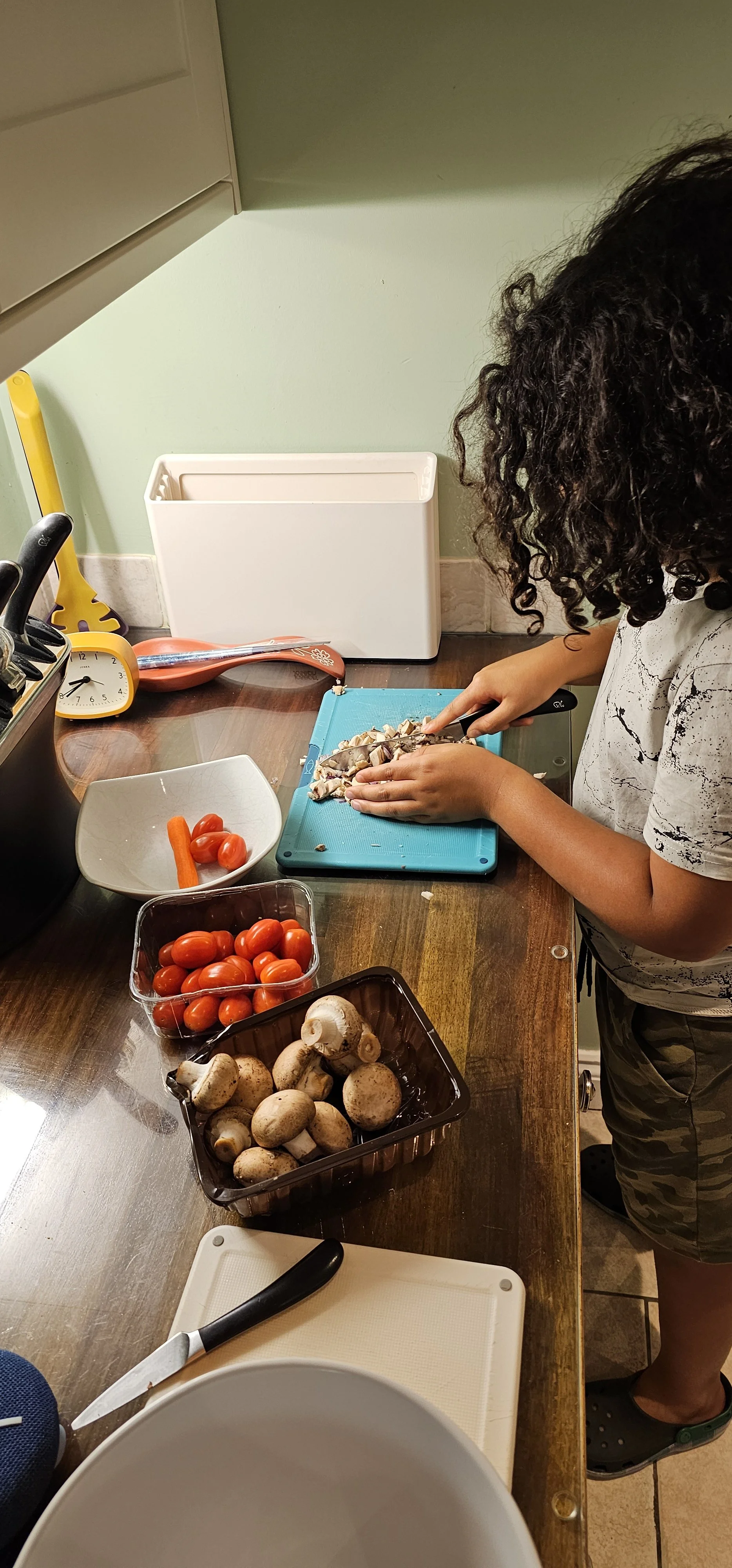 Child using Robert Welch chefs knife in a kitchen setting to chop mushrooms during a cook class