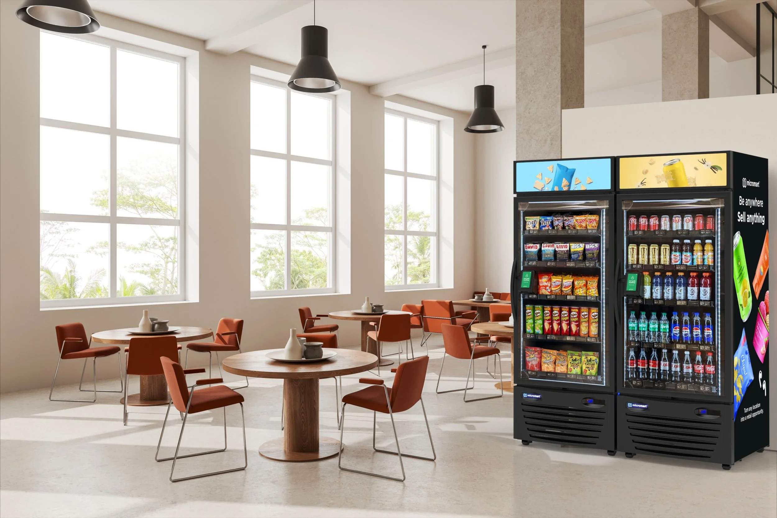 A modern cafe or lounge area with round wooden tables, orange chairs, and large windows. There are black pendant lights hanging from the ceiling and vending machines with snacks and drinks on the right side.