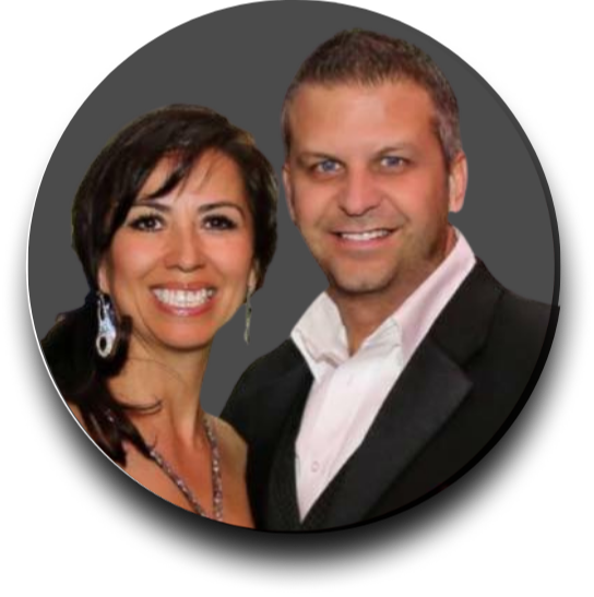 A smiling woman with dark hair and earrings standing next to a smiling man in a suit.