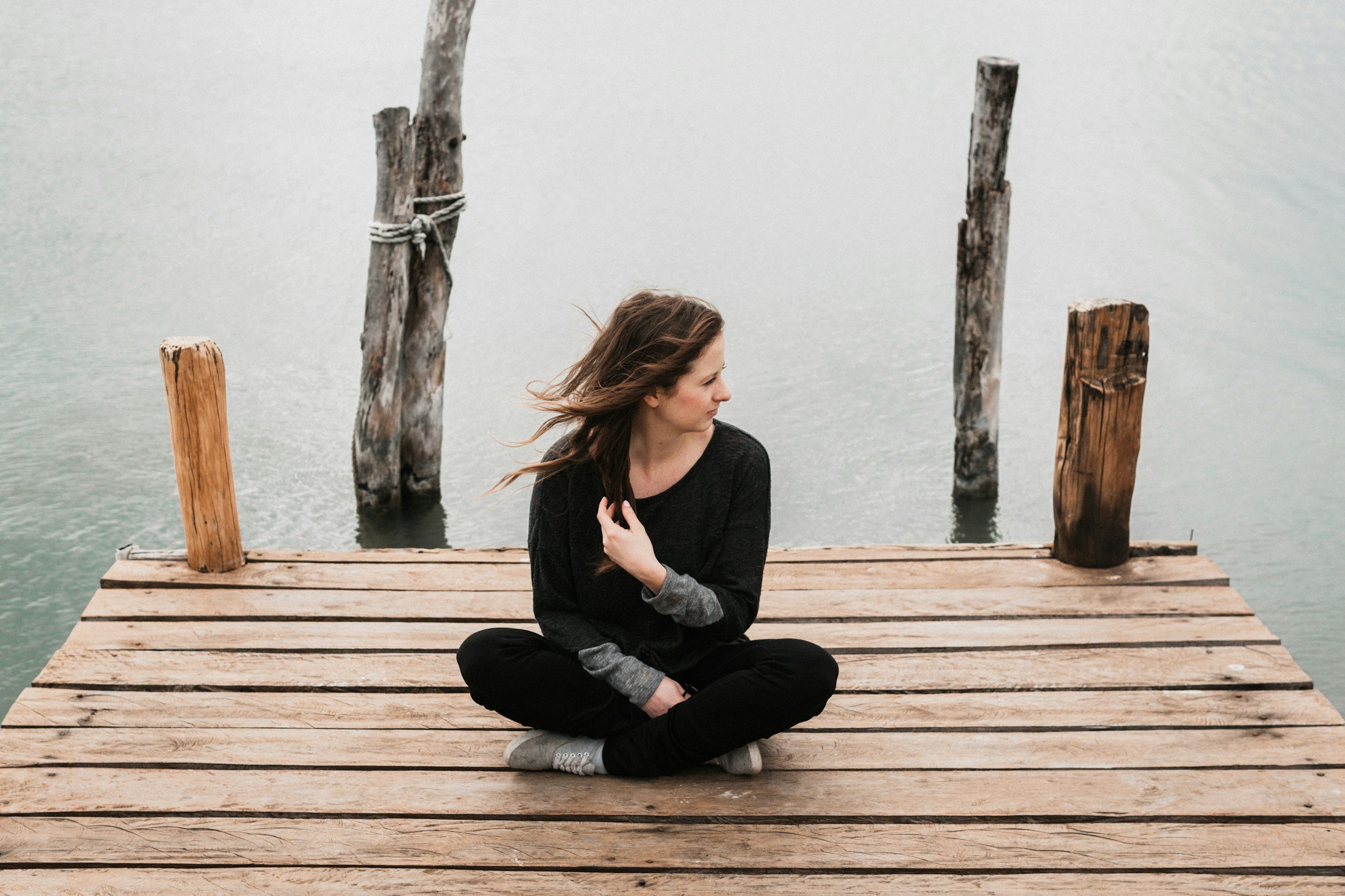 woman sitting on a dock with water behind her