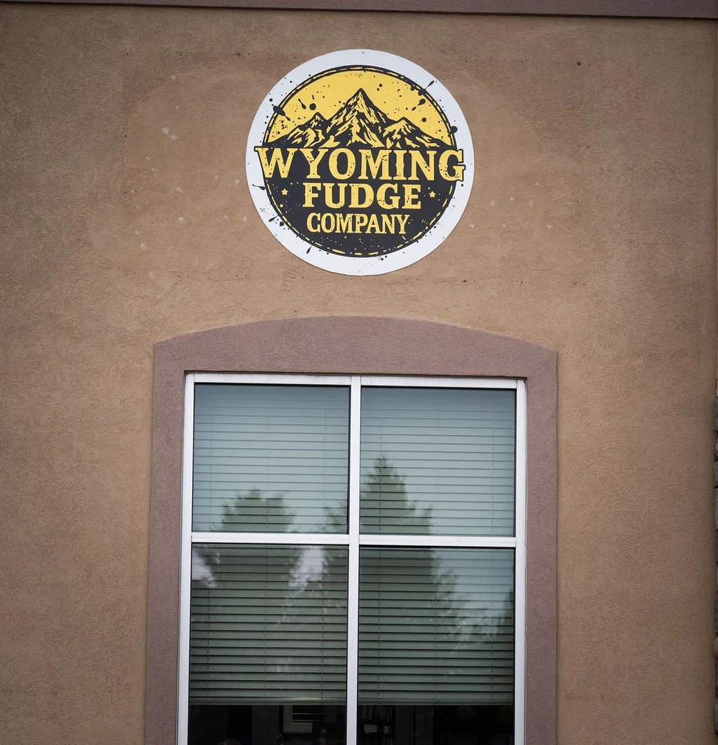 Sign for Wyoming Fudge Company above a window on a building.