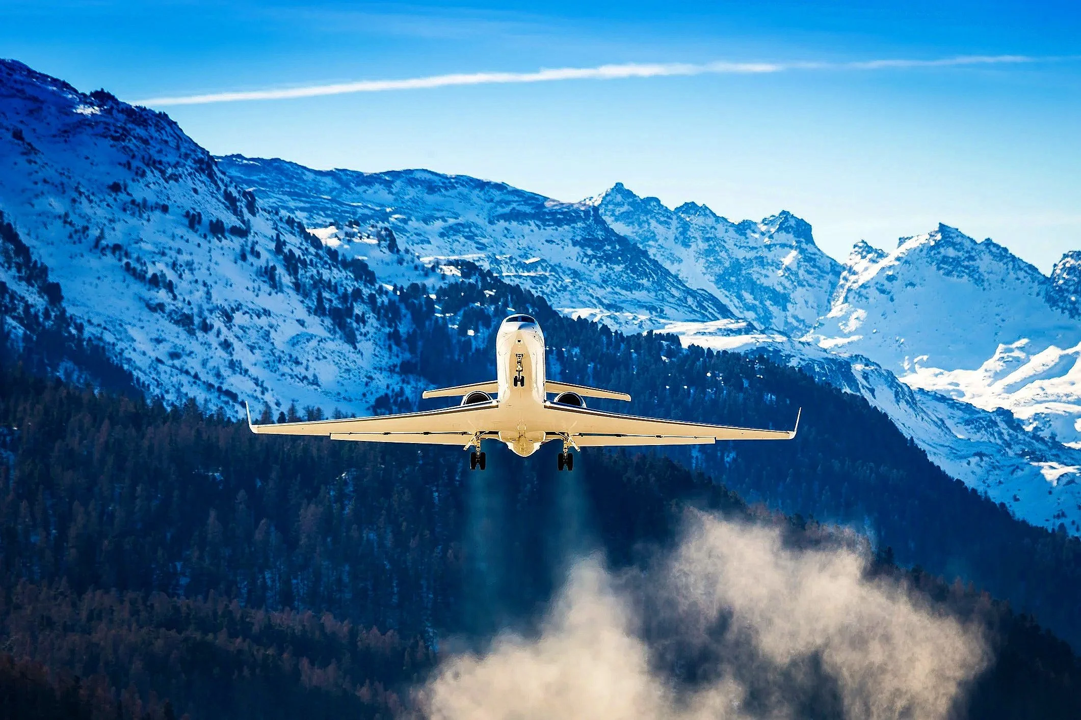 A large cabin jet takes off, surrounded by snowcapped mountains.