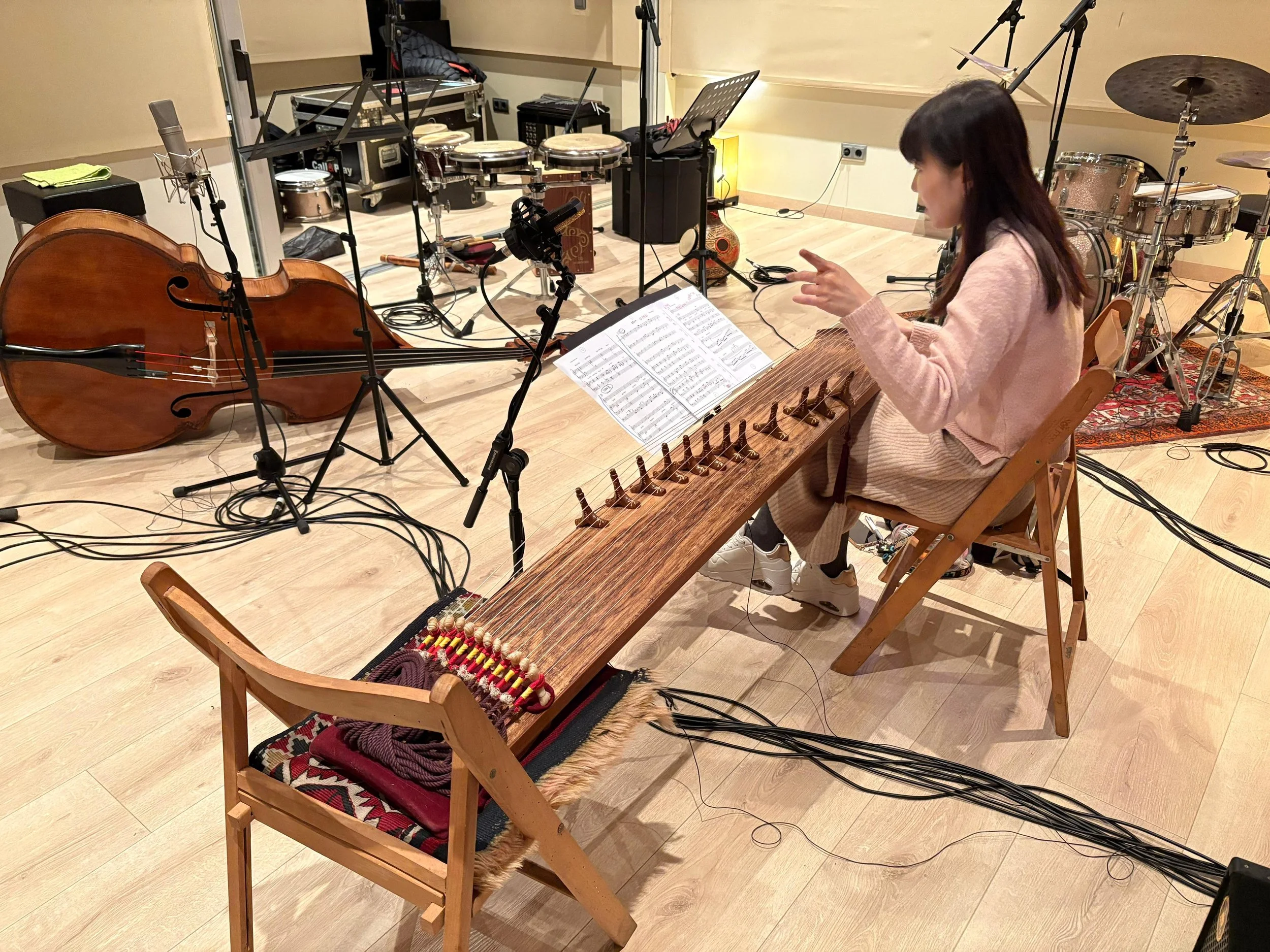 Mujer tocando el clavicordio en un estudio de grabación con instrumentos y micrófonos alrededor.