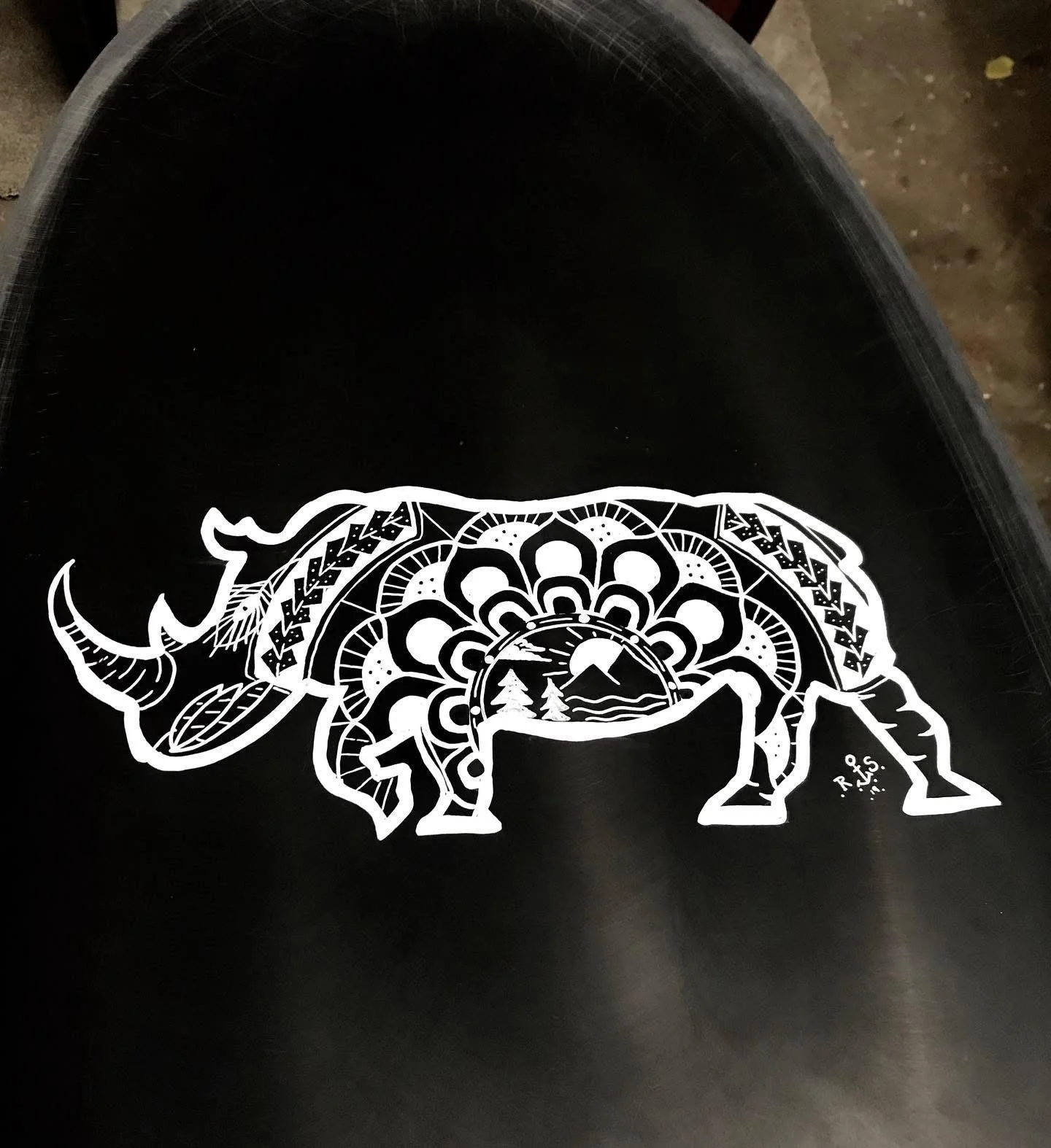 Decorative black surface with a white intricate illustration of a buffalo with landscape scene inside its body, including mountains, trees, and water.