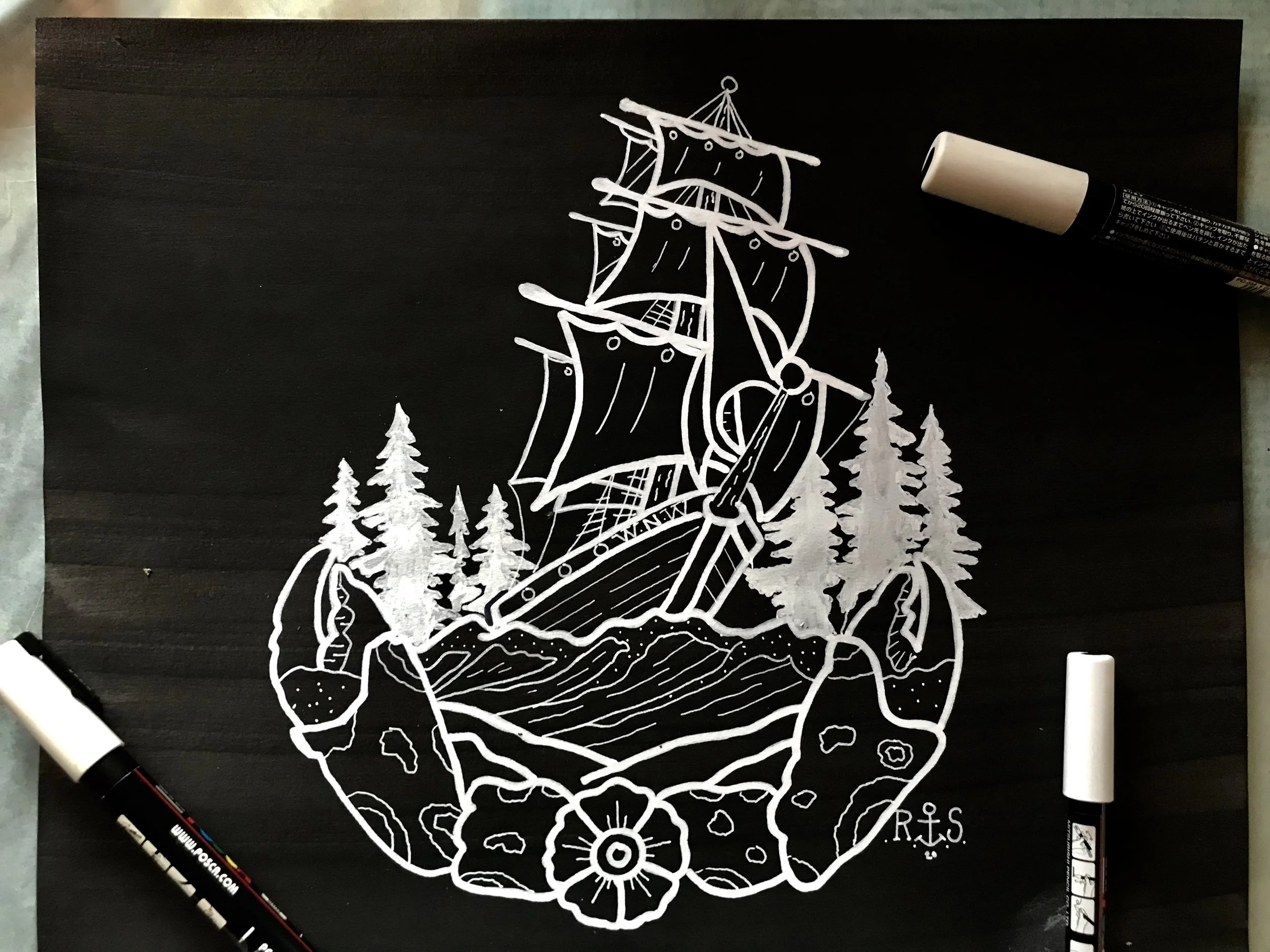 White chalk drawing of a ship with sails on a stylized landscape with trees, rocks, and flowers, on a blackboard or dark surface, with chalk markers nearby.