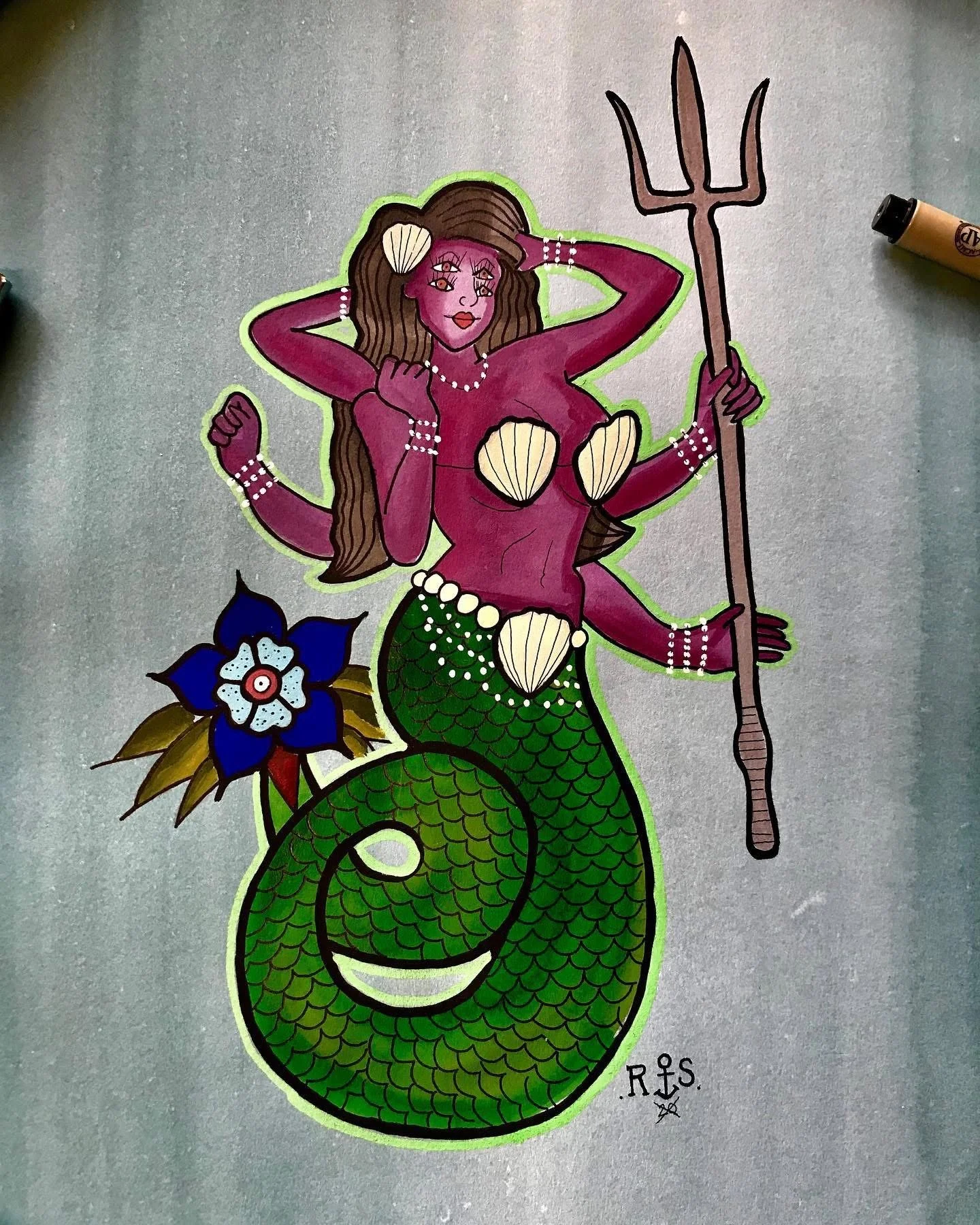 A colorful drawing of a mermaid with purple skin, long brown hair, and shell jewelry, holding a trident, with a blue flower and seashell decorations.
