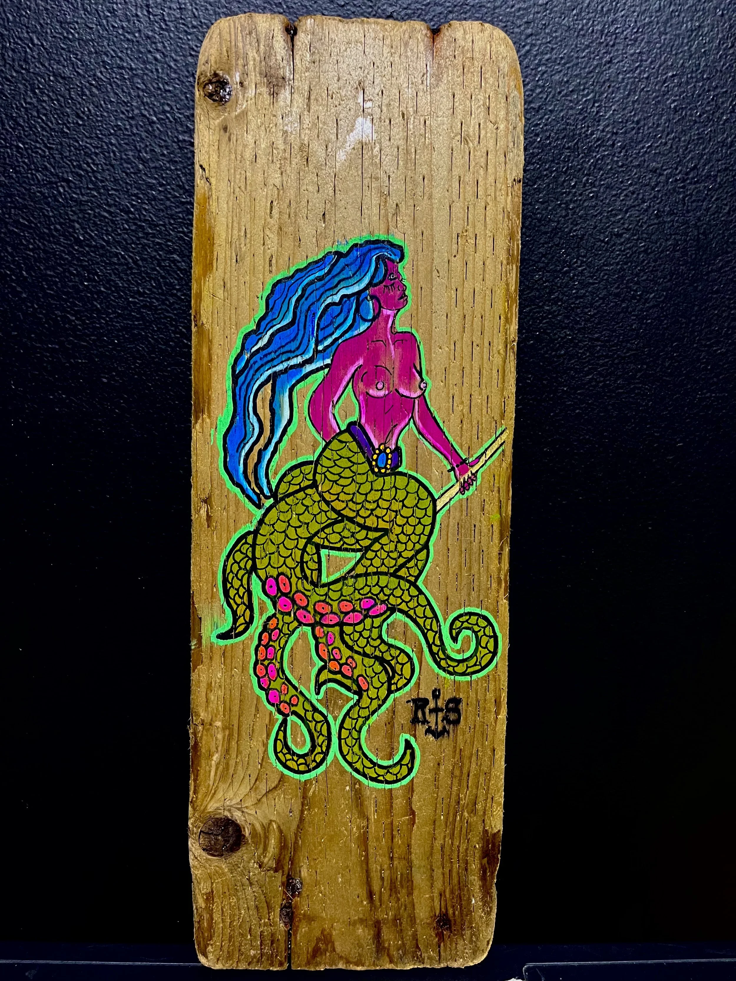 Colorful illustration of a mermaid with blue hair and scales, holding a sword, painted on a wooden plank.