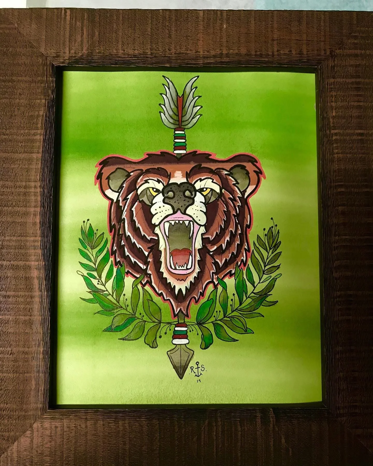 A drawing of a roaring lion's head with a feathered arrow through its mane, surrounded by green leaves on a bright green background.
