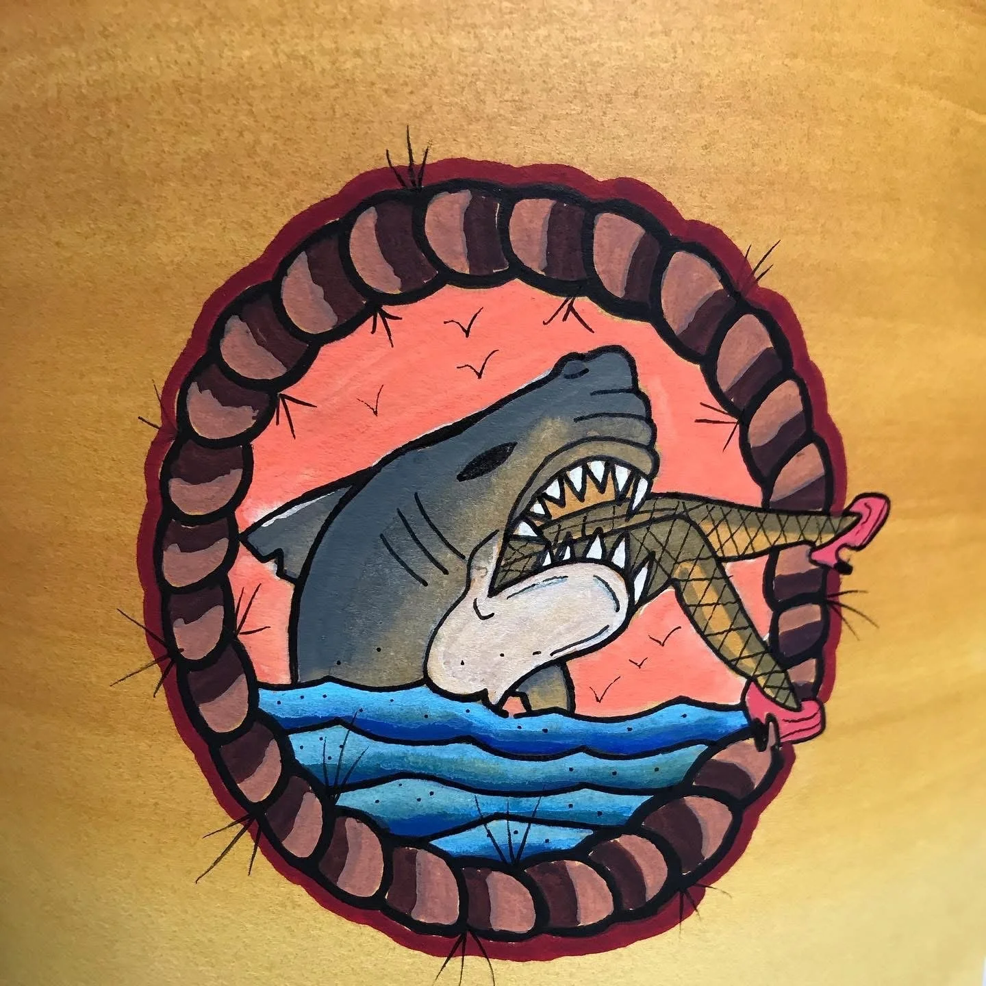 A drawing of a shark biting into a fish, with a sunset or sunrise background and birds flying in the sky, surrounded by a circular border.