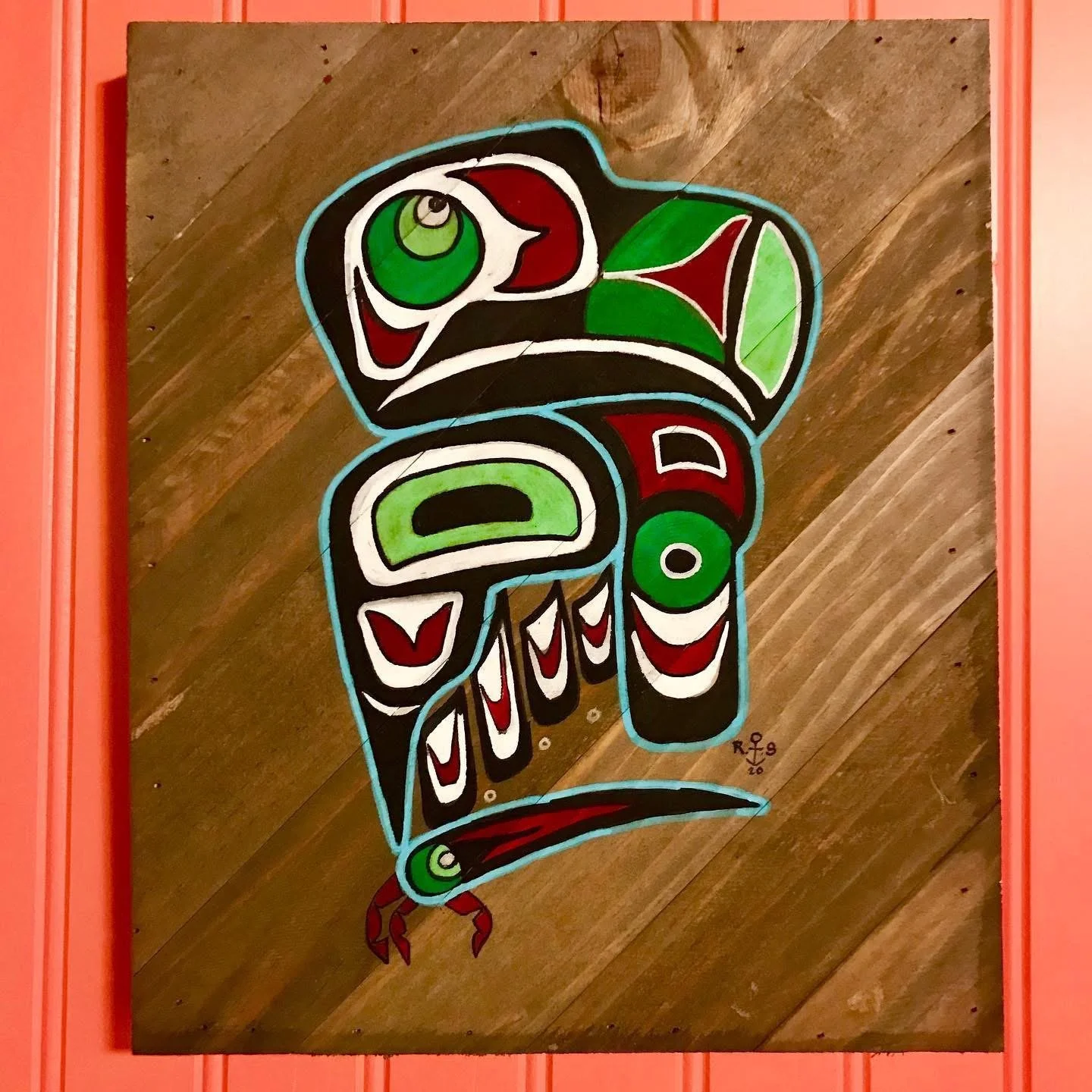 A colorful, stylized painting of a Thunderbird, a mythic bird, with bold outlines and vibrant colors including green, red, white, and black, mounted on a wooden wall.