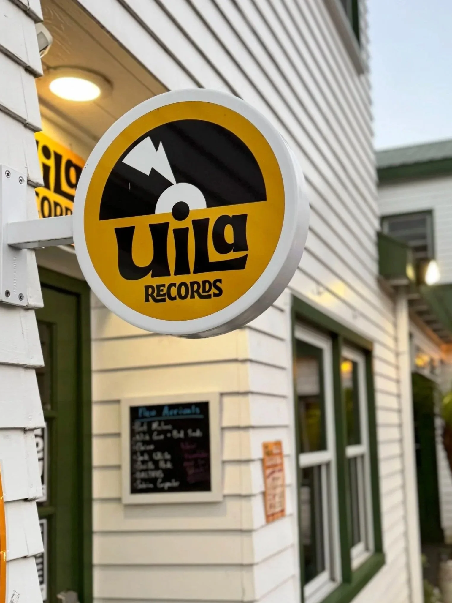 Sign for Willow Records outside a building with white siding and green window frames.