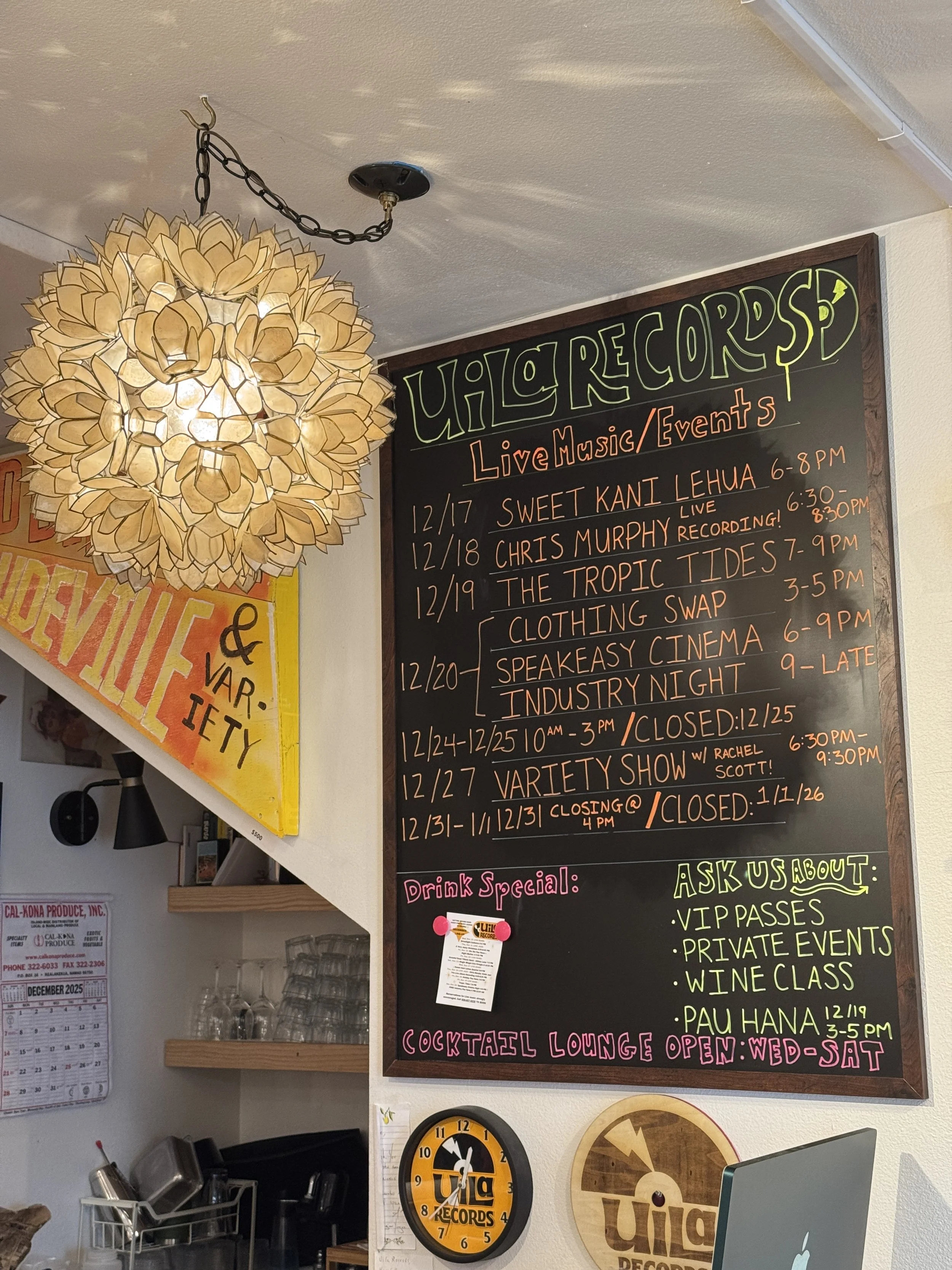 A large blackboard menu displays upcoming live music and event schedule at UH/O Records, with dates and times listed for performances from December 17 to December 31, including details about specific shows, and a section about drink specials, private