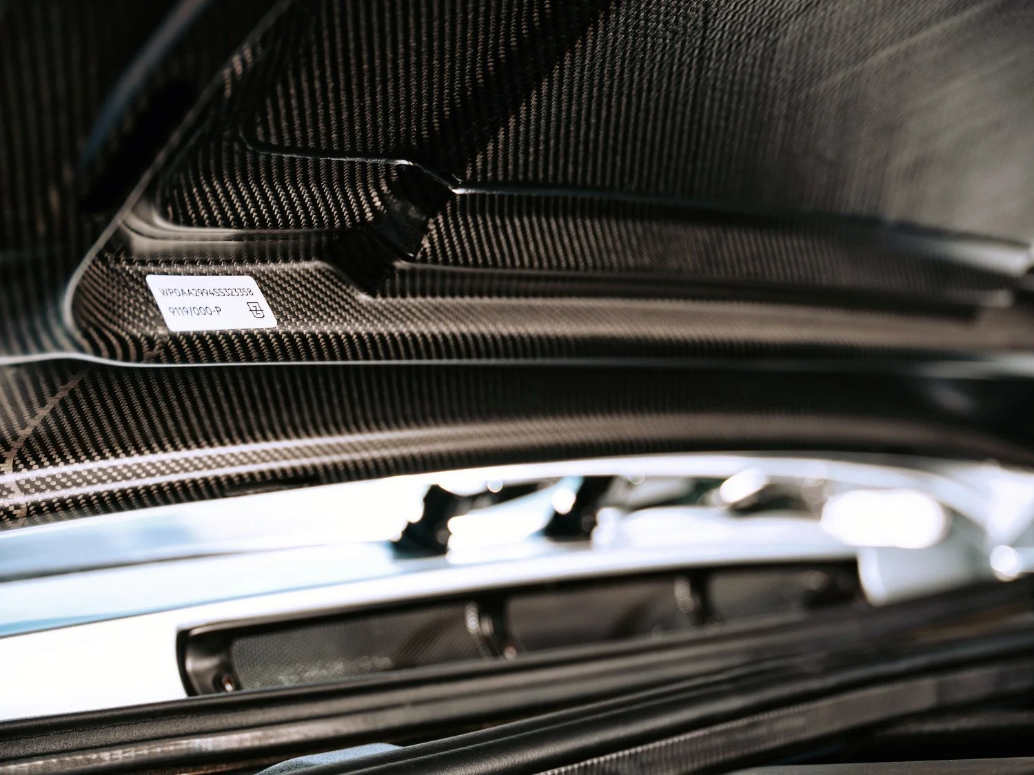 Close-up of a black car interior with carbon fiber accents and a visible serial number label.