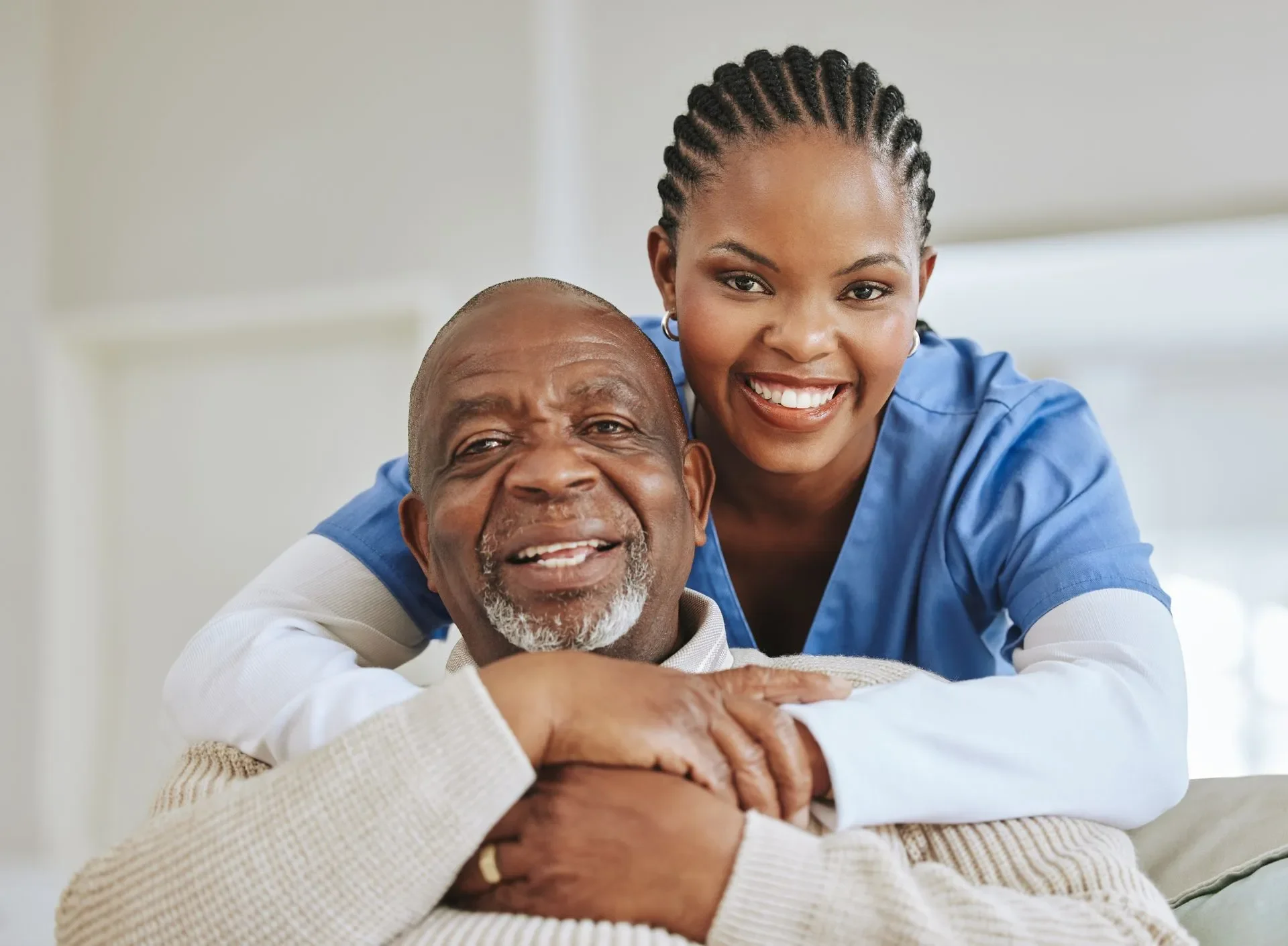Smiling healthcare workers, a young woman and an older man, posing together in hospital scrubs and casual clothing.