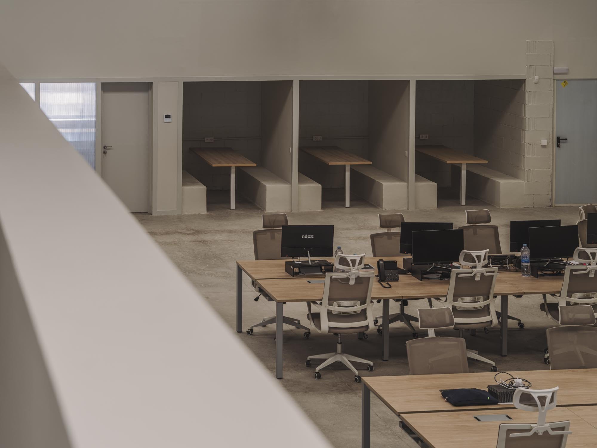 Espacio de oficina con varias mesas de trabajo, computadoras y sillas en un ambiente de oficina moderna.